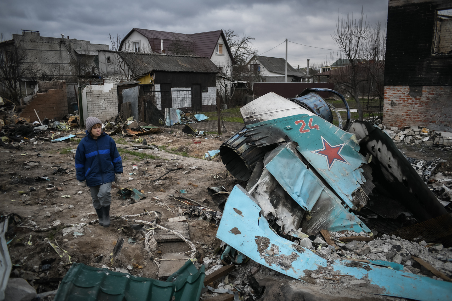 Chernihiv, Ukraine. 16th Apr 2022. A woman walks on rubbles on the site where a destroyed Russian Sukhoi Su-34 crashed on a residential area of Chernihiv, Ukraine on April 16, 2022. The pilot managed to eject and was captured, his navigator has been killed. 
