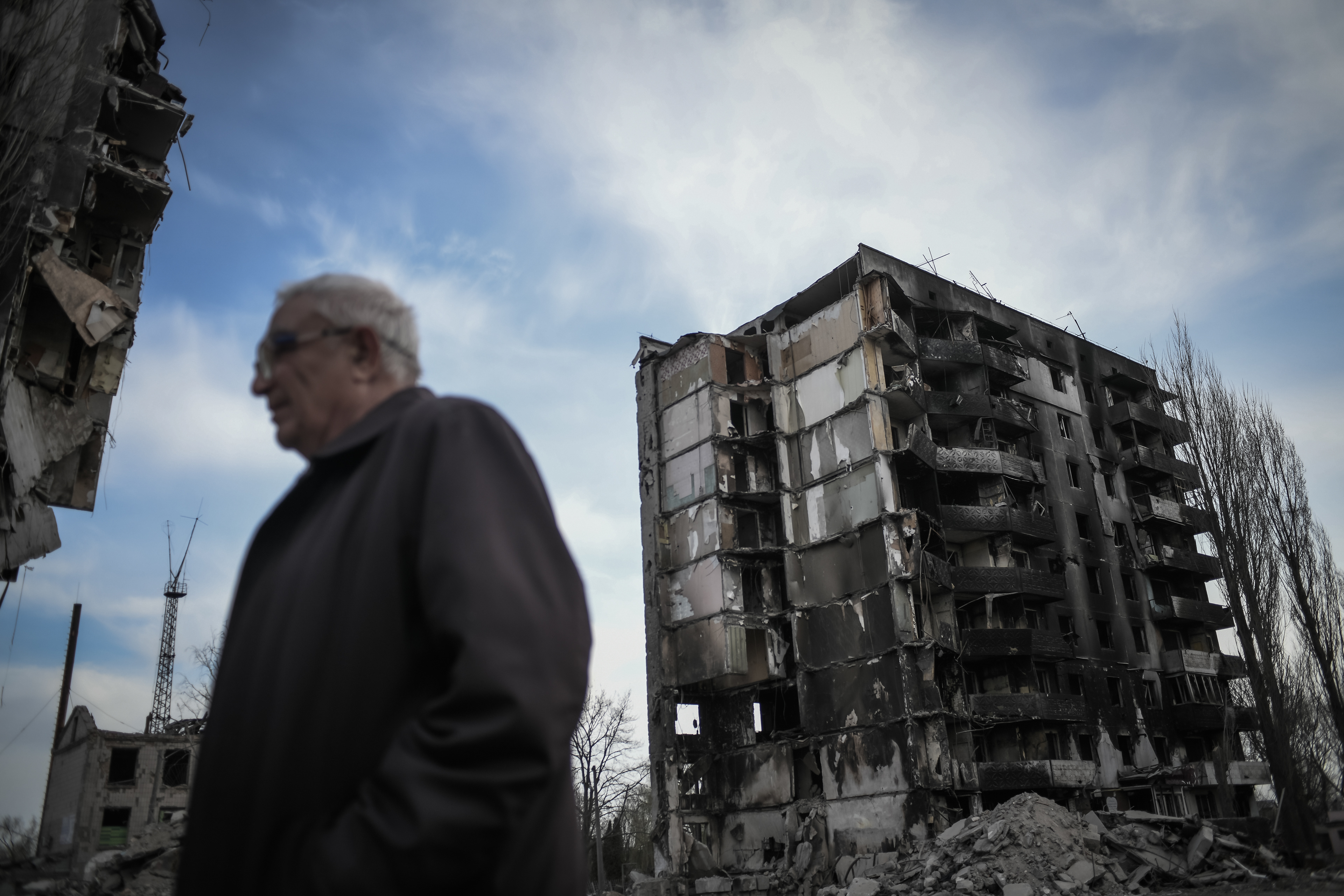 Borodyanka, near Kyiv, Ukraine - April 15, 2022: a man walks in front of buildings damaged by shelling in central Borodyanka during Russian occupation