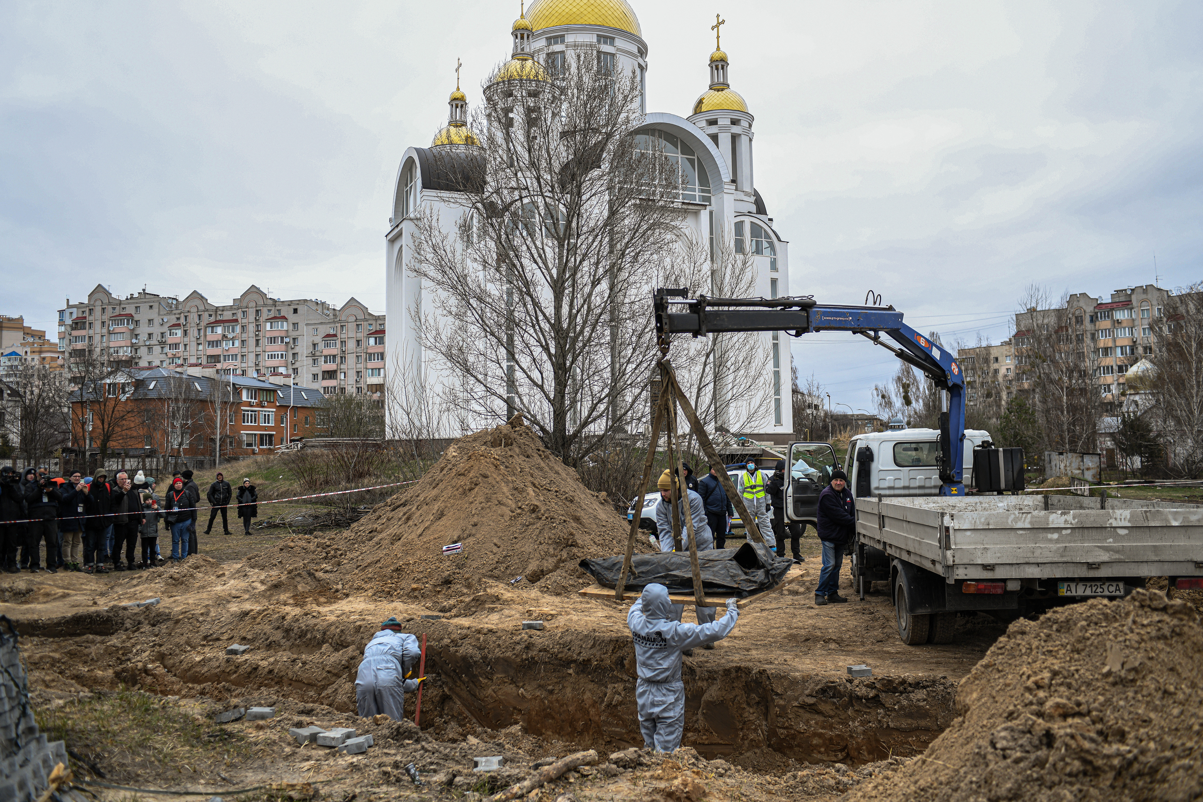 Bucha, Kyiv, Ukraine - April 13, 2022: people exhume from a mass grave bodies of civilians killed during the Russian occupation of Bucha