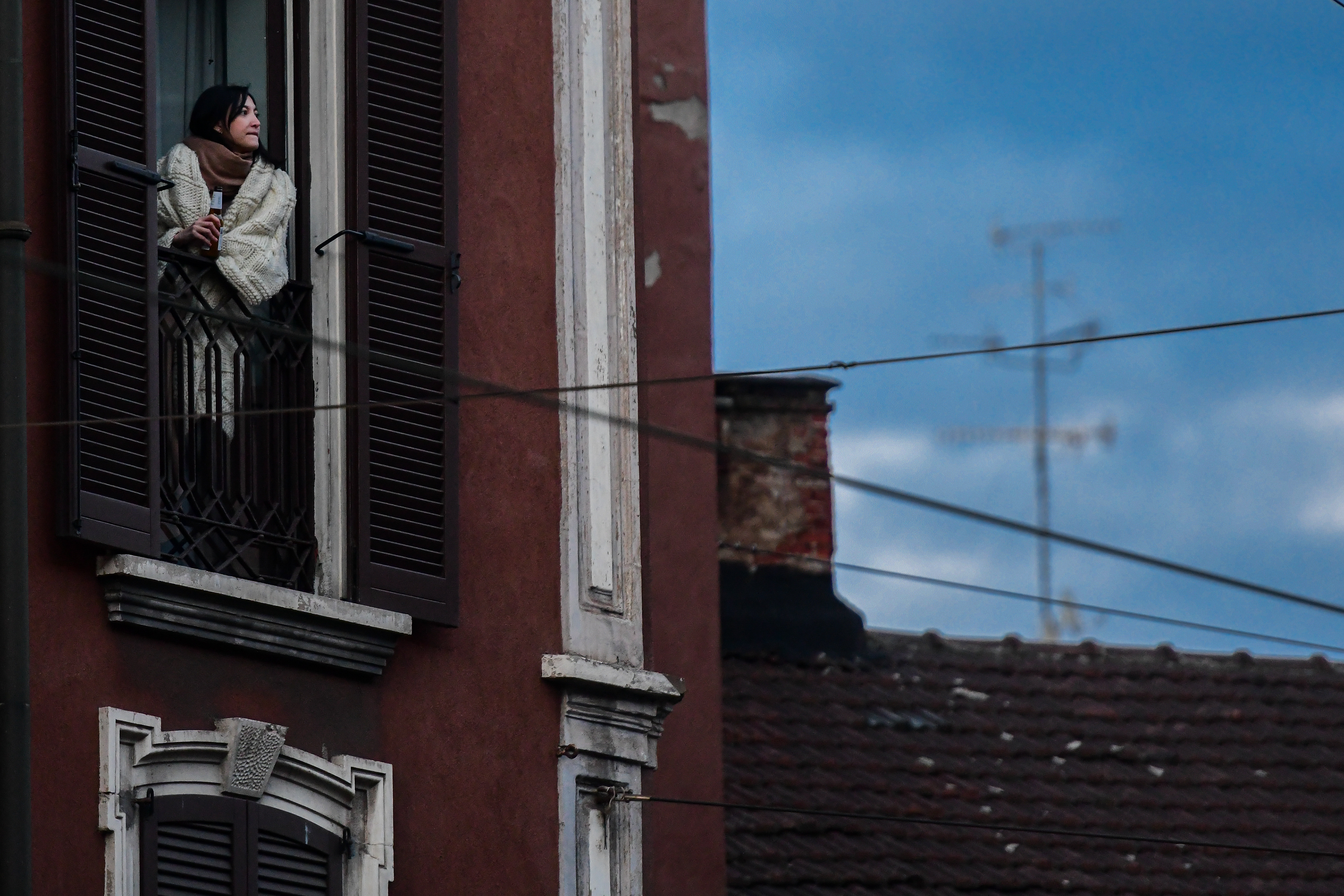 Milan, Italy - 14 March 2020: A woman looks on on her balcony during a flashmob launched to show unity against coronavirus.