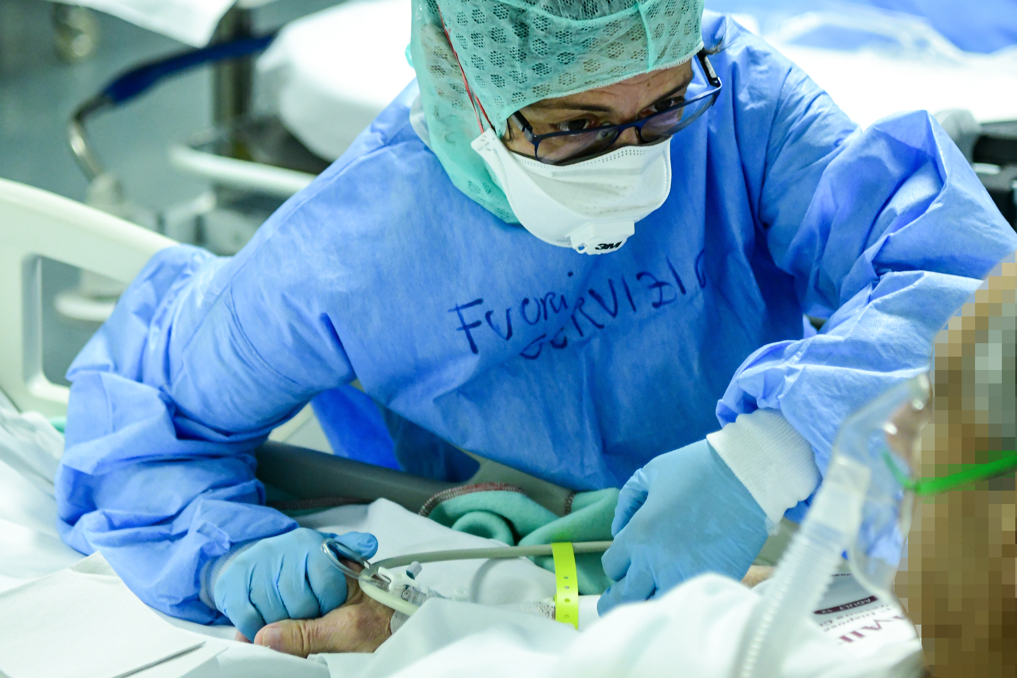 A Medical worker holds the hand to a patient in the ICU unit at the ASST Papa Giovanni XXIII hospital in Bergamo, Italy on April 3, 2020 