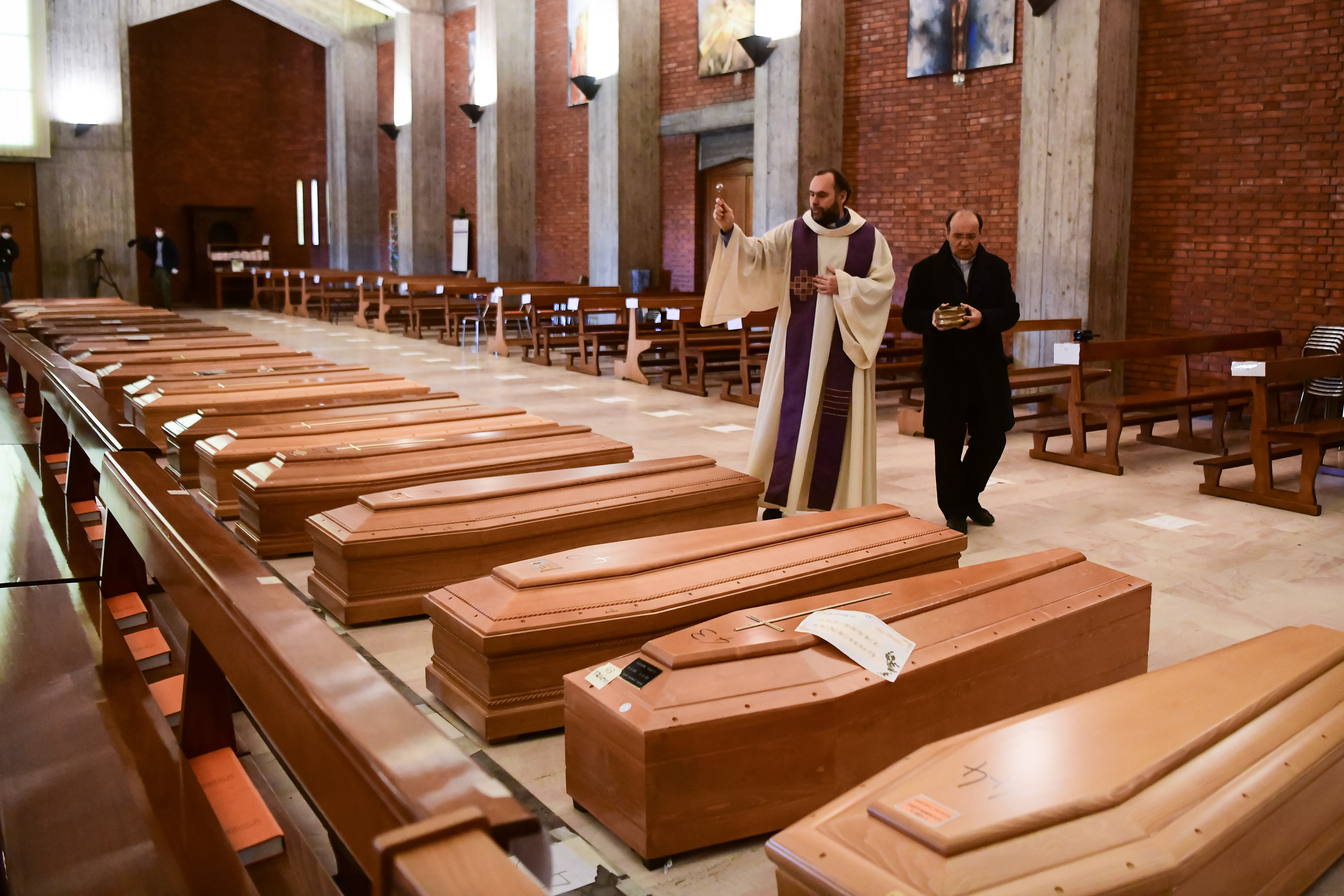 Priest Don Marcello gives a blessing to the coffins of deceased people inside the church of San Giuseppe in Seriate, Italy on March 28, 2020