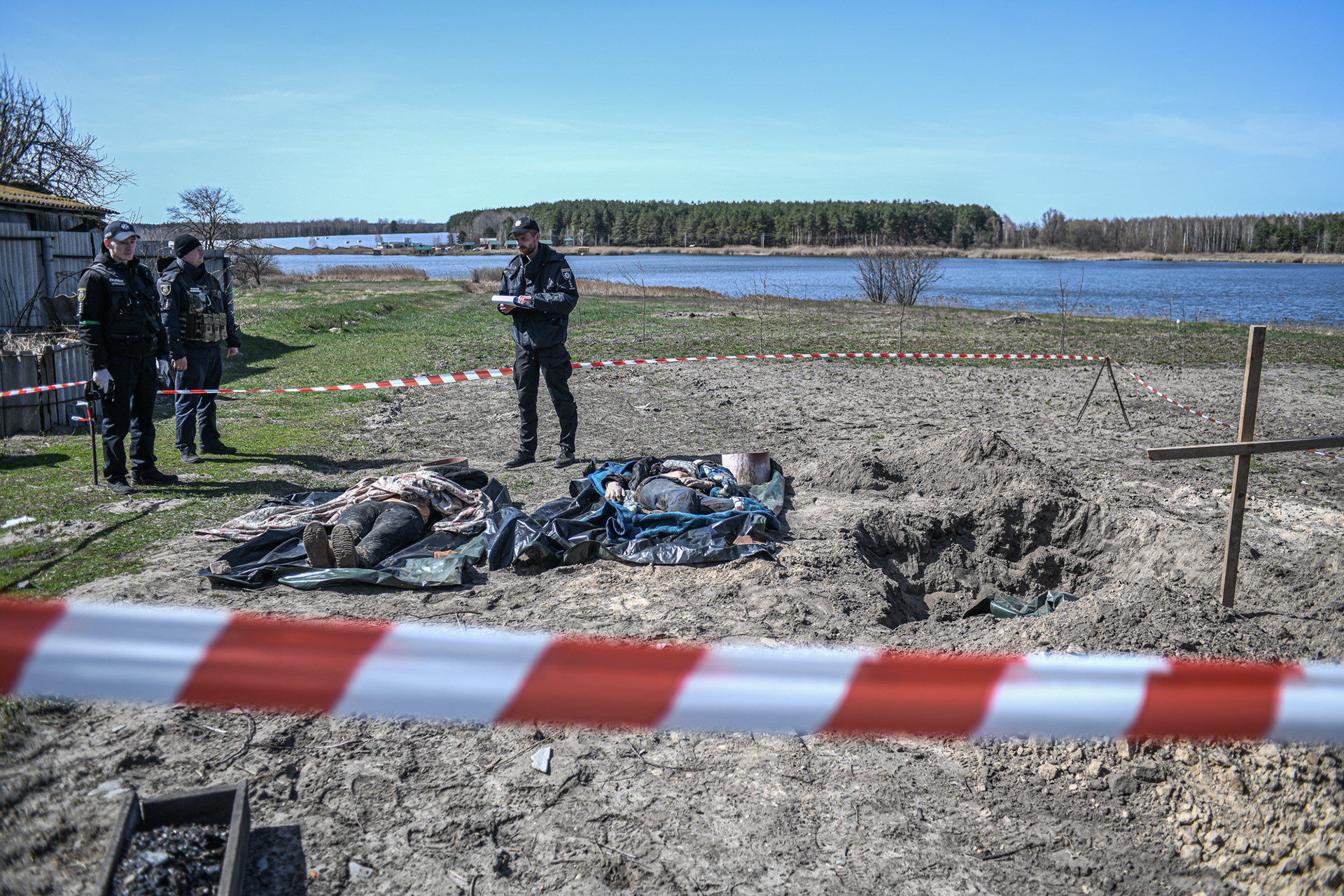 Voblya, near Kyiv, Ukraine - April 14, 2022: Police officers exhume and investigate the bodies of a woman, 52 and her son, buried by neighbours in their garden after being killed during the Russian military occupation. 