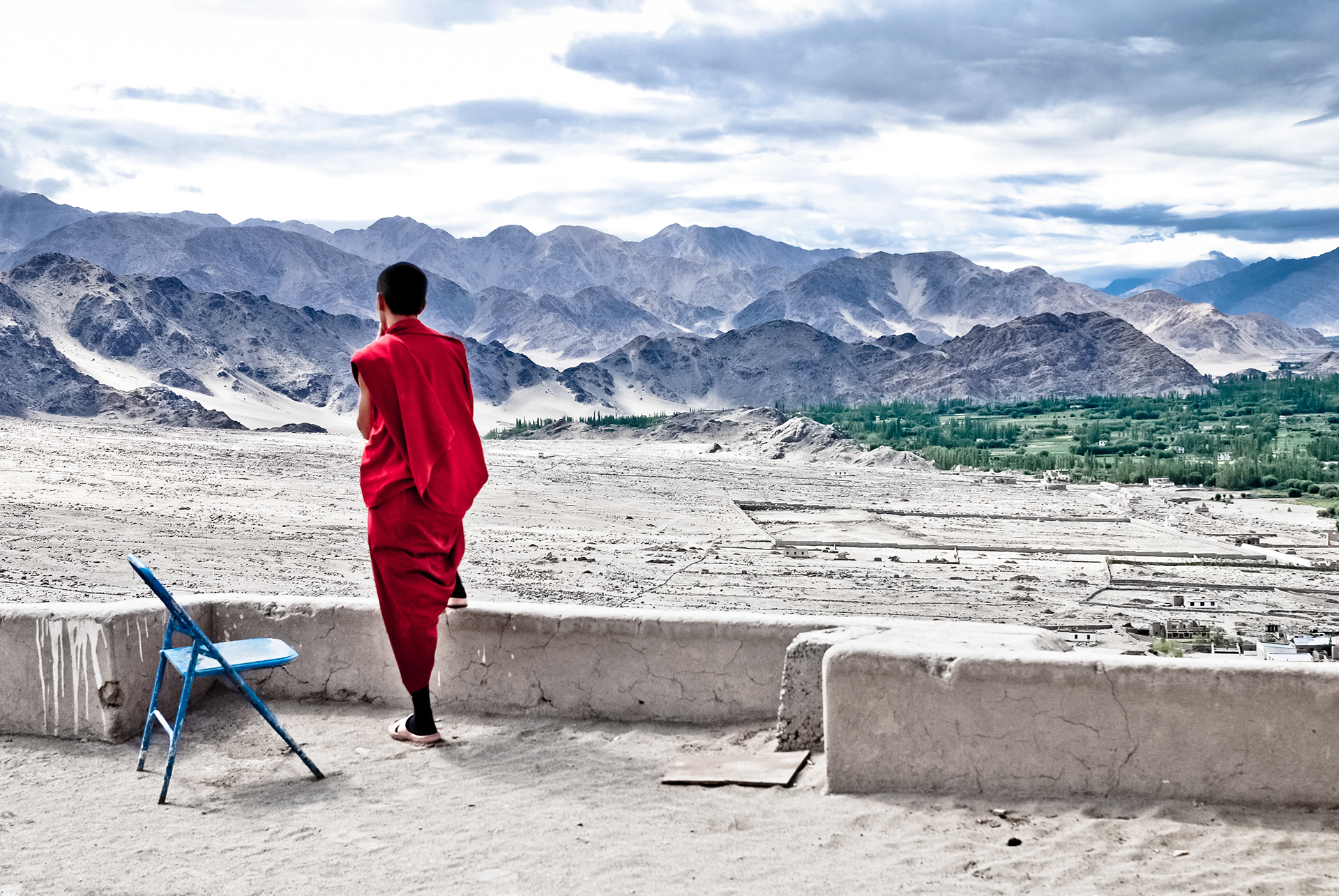Ladakh, India - July 2009: a Buddhist monk contemplating the mountainous view from the terrace of a monastery