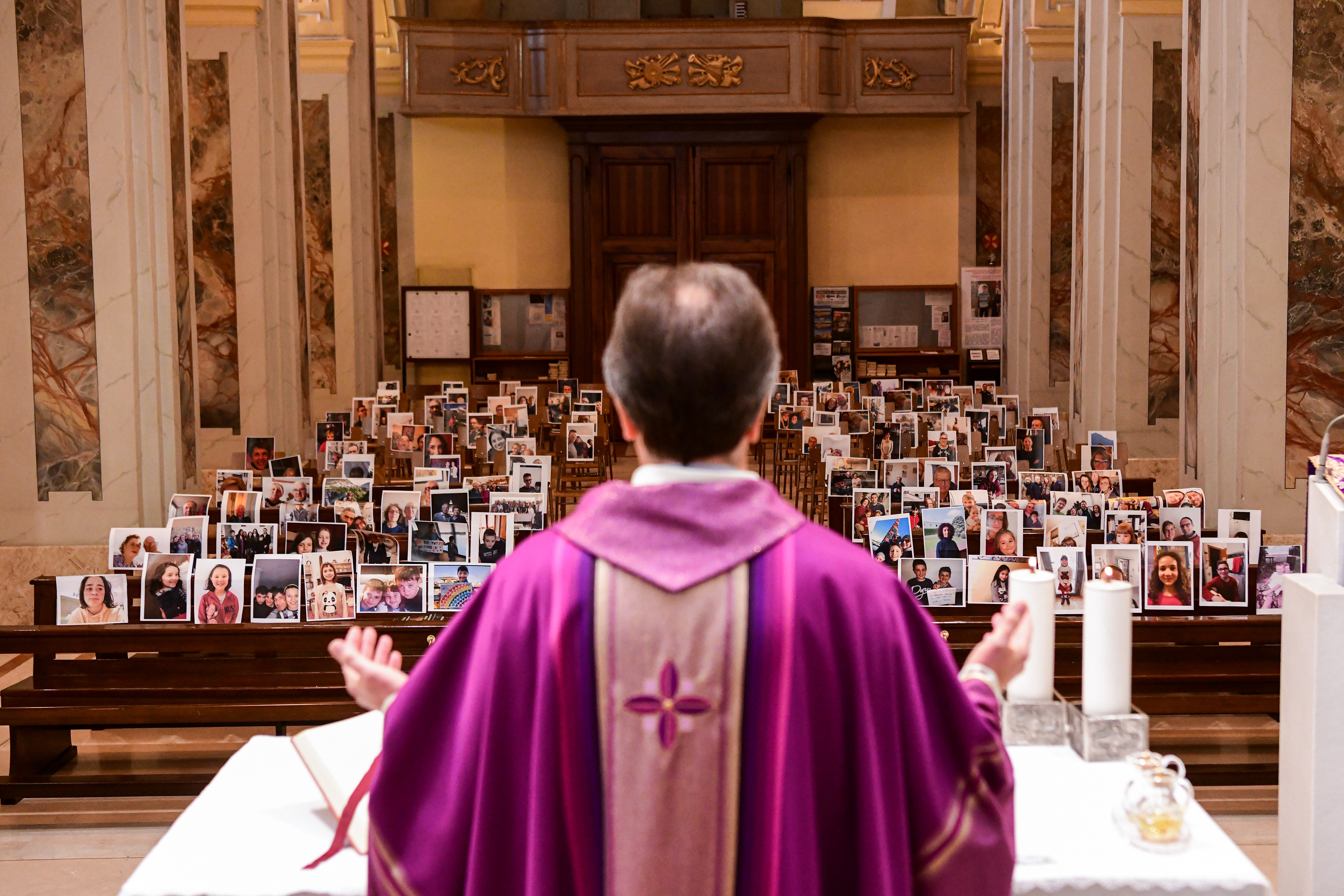 Don Giuseppe Corbari, parson of the Church of Robbiano, celebrates mass in front of empty church pews adorned with selfies sent by his congregation, in Giussano, Italy on March 22, 2020. Public Masses have been suspended due to concerns over Covid-19 outbreak.