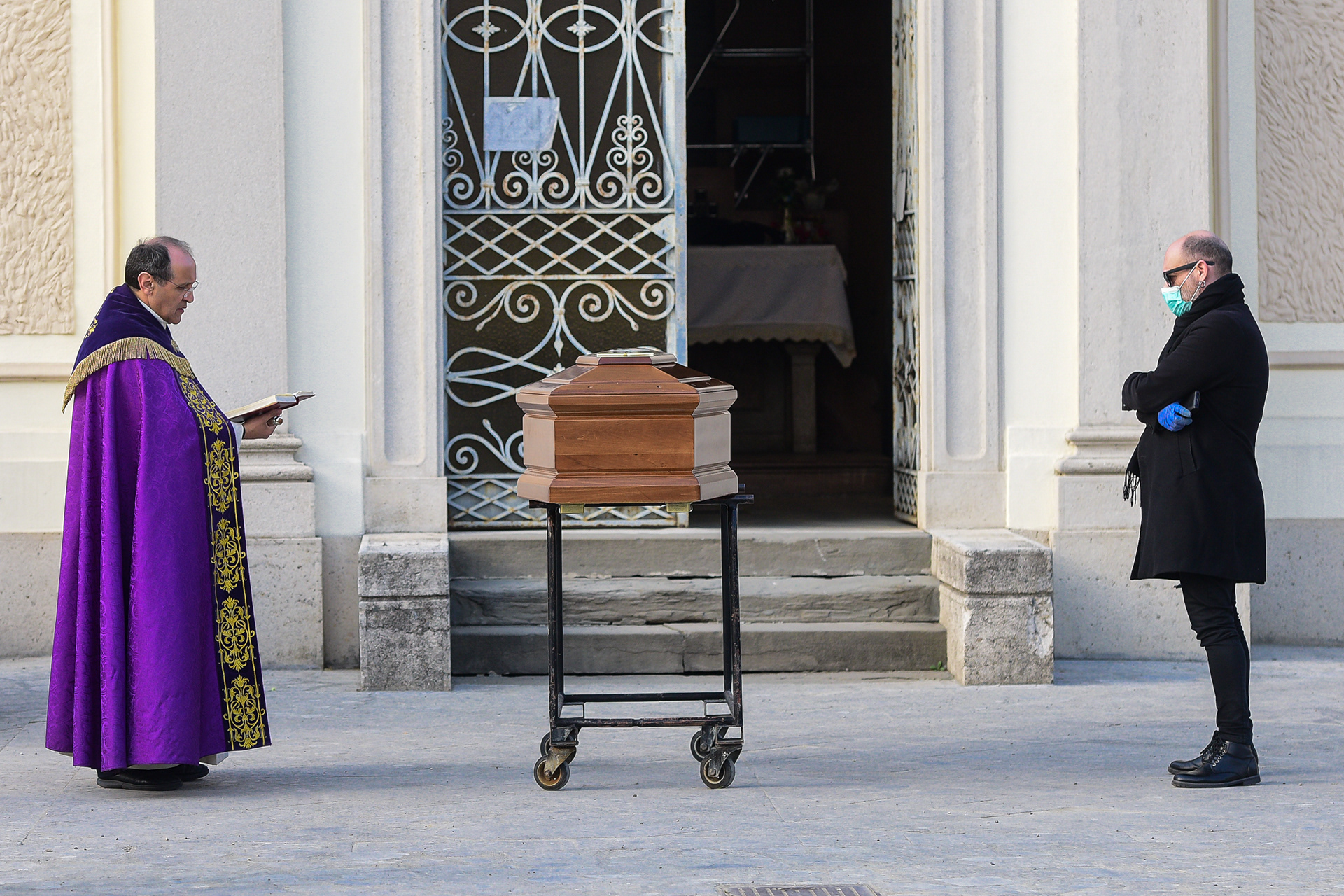 A man looks at the coffin bringing the body of her mother during a closed-doors funeral service in the cemetery of Seriate, Italy on March 20, 2020. photographer milan, fotografo milano