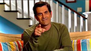 Image of the character Phil Dunphy sat in his living room pointing at camera in the show Modern Family