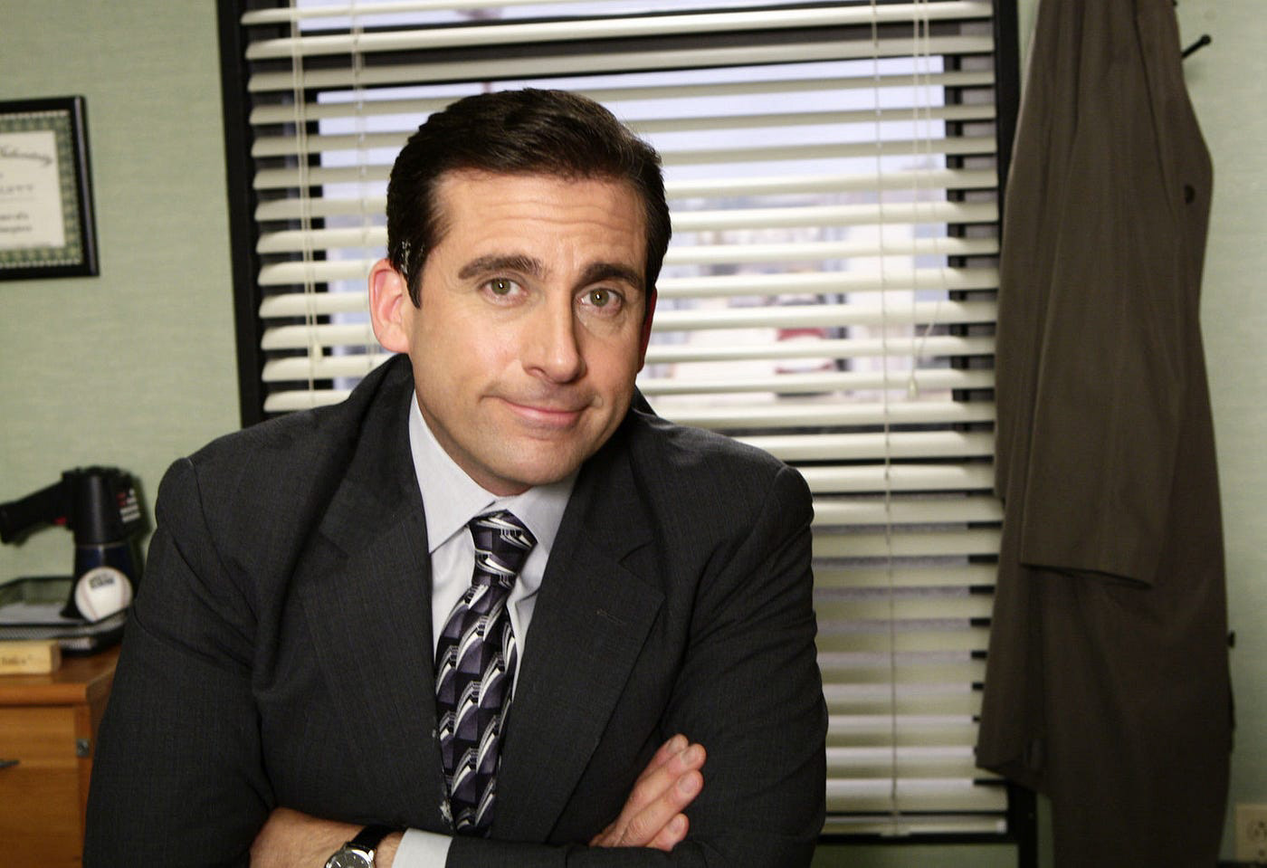 Character of Michael Scott from the Office (US) sat behind his desk smiling