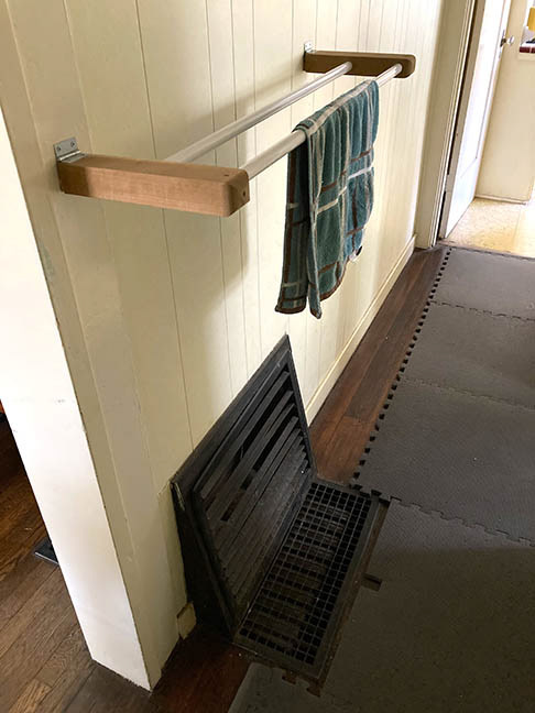 Recycled rods for drop-down drying rack over old floor heater.