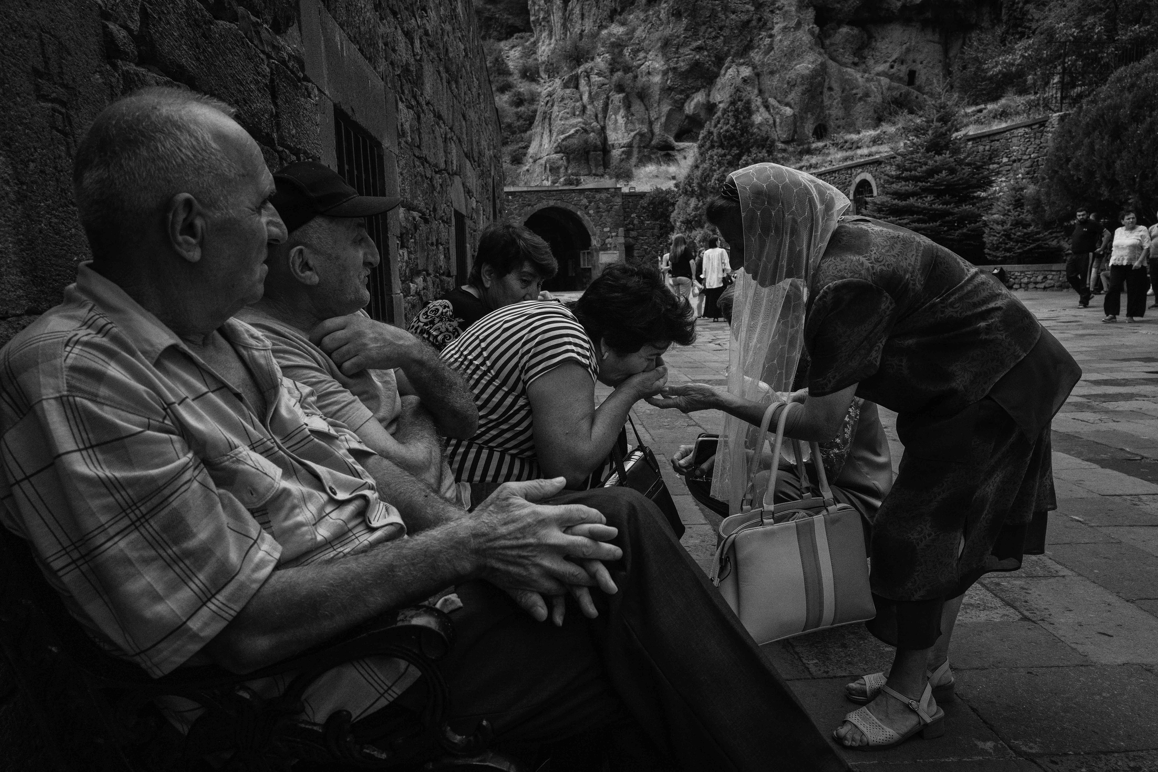 Geghard Monastery, a lady brings water to friends outside the monastery walls. Armenia 2024.