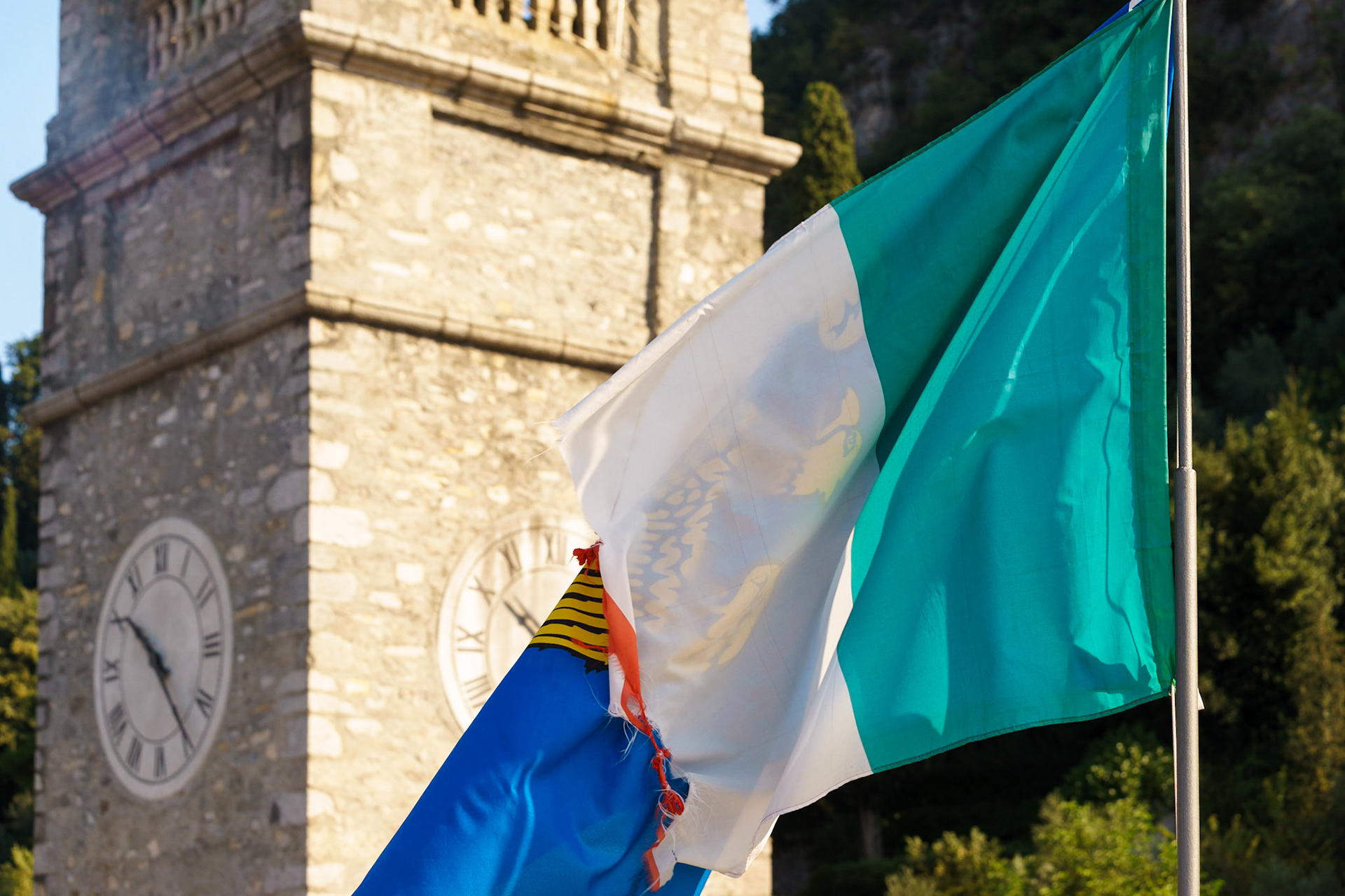 Como Gölü çevresindeki köylerden biri olan Varenna'nın saat kulesi ve rüzgardan hırpalanmış bir İtalya bayrağı.