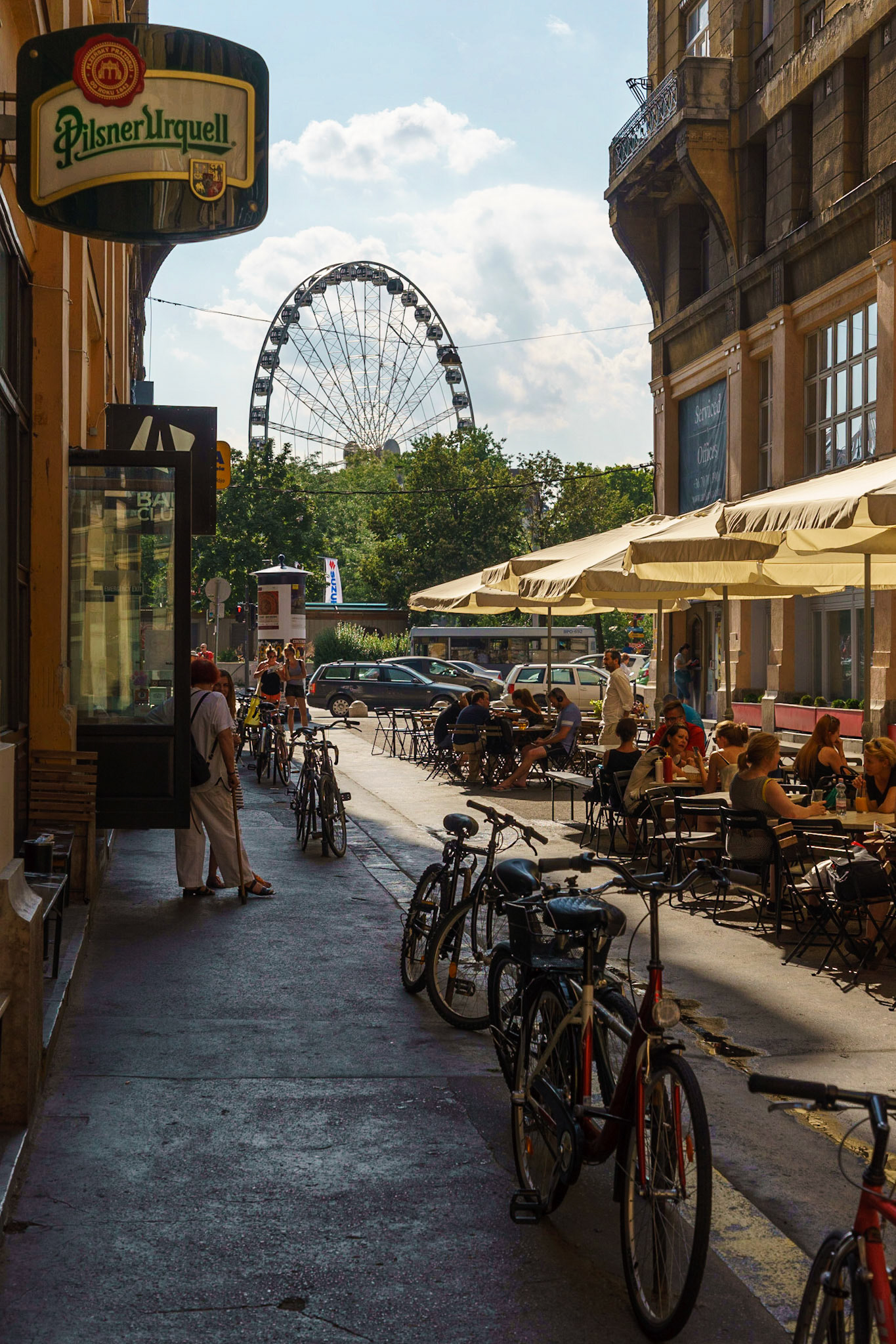 Budapeşte'yi özetleyen bir manzara: bisikletler, yeşillik, tarihi binalar ve sokakta keyif yapan insanlar.