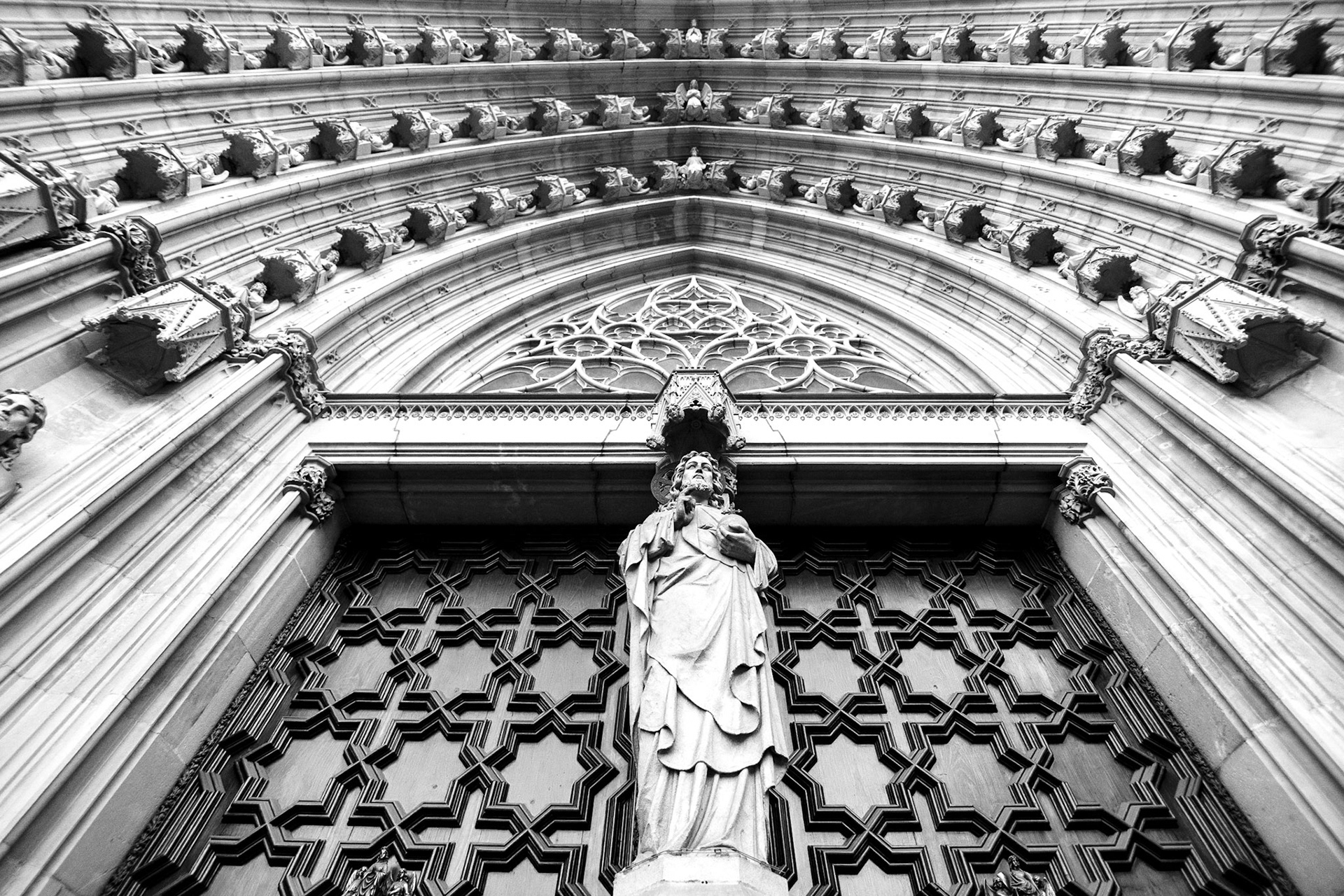 Barselona Katedrali'nin girişinde ziyaretçileri karşılayan İsa heykeli ve nefes kesici detaya sahip kapı kemeri.