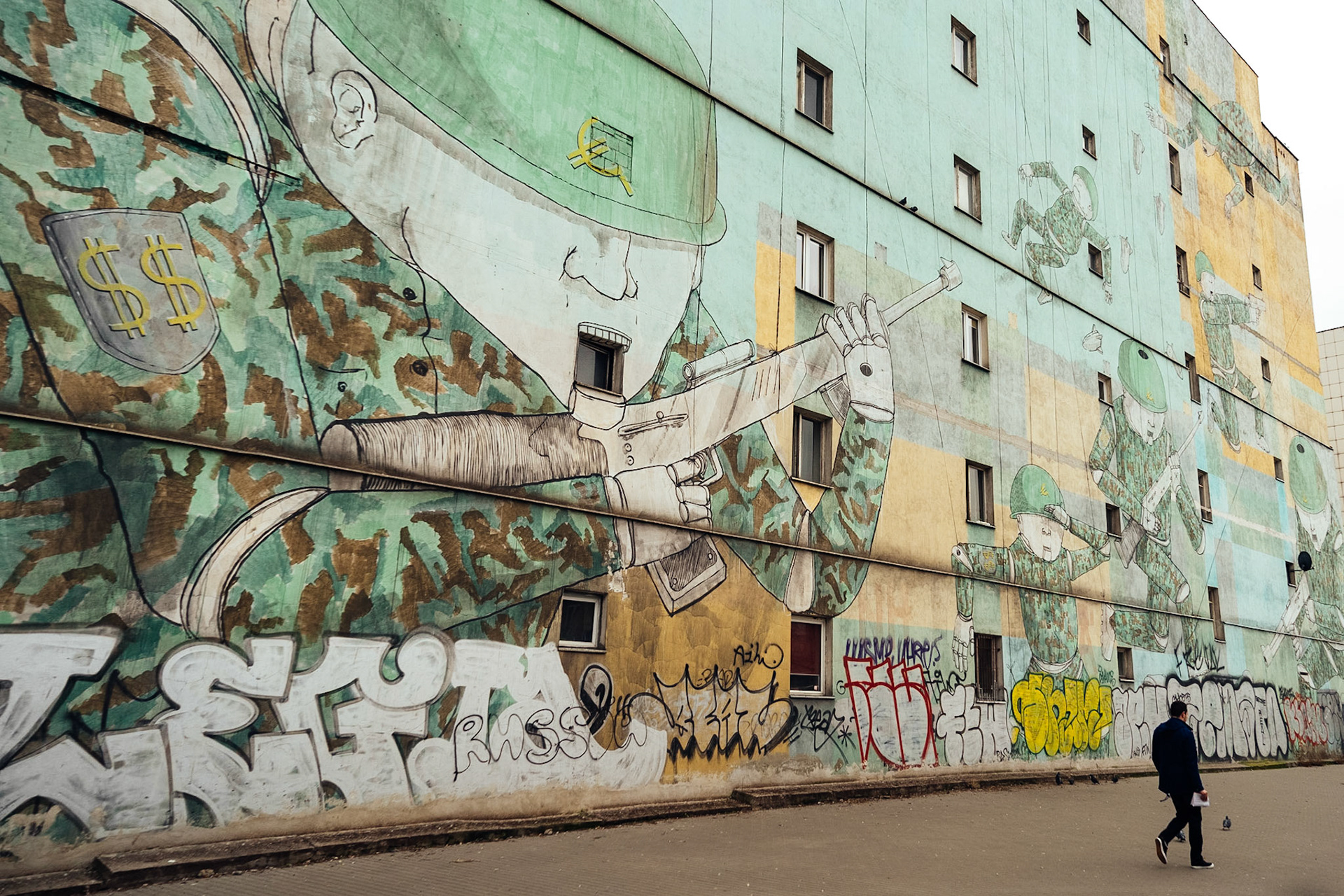 Ünlü İtalyan sokak sanatçısı Blu tarafından yapılan duvar resmi. Eserde dolar ve euro simgeli armalar taşıyan, kukla ipleriyle asılı duran askerler resmediliyor.