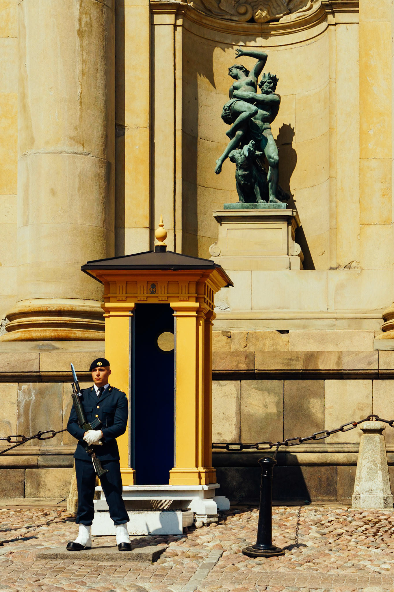 Kraliyet Sarayı'nın önünde nöbet tutan bir muhafız, ve hemen arkasında yer alan heykellerin manzarası.