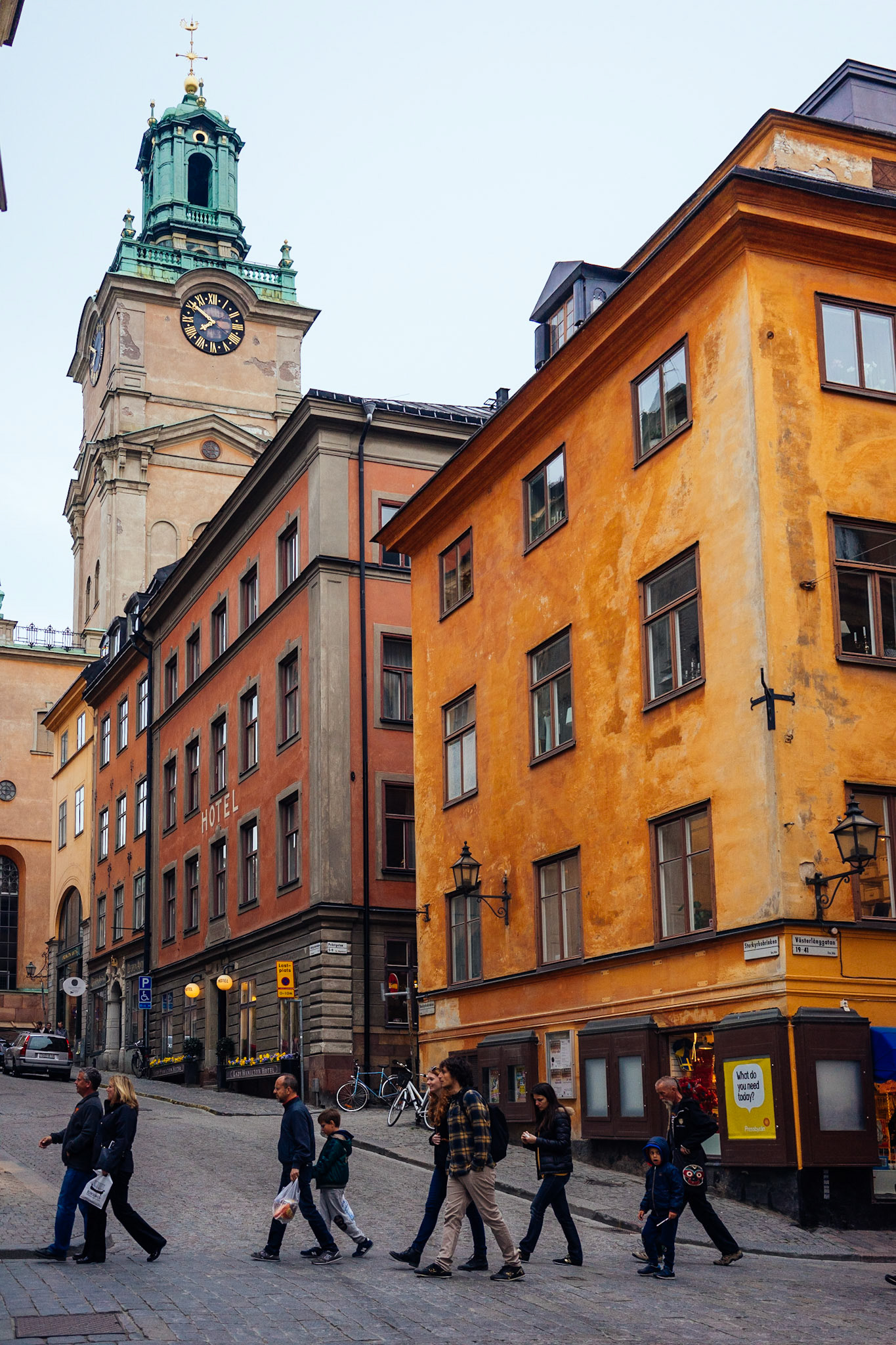 Arkaplanda Stokholm'ün en eski kilisesi olan Storkyrkan ile birlikte, Gamla Stan'ın sokaklarında gezen bir turist grubu.