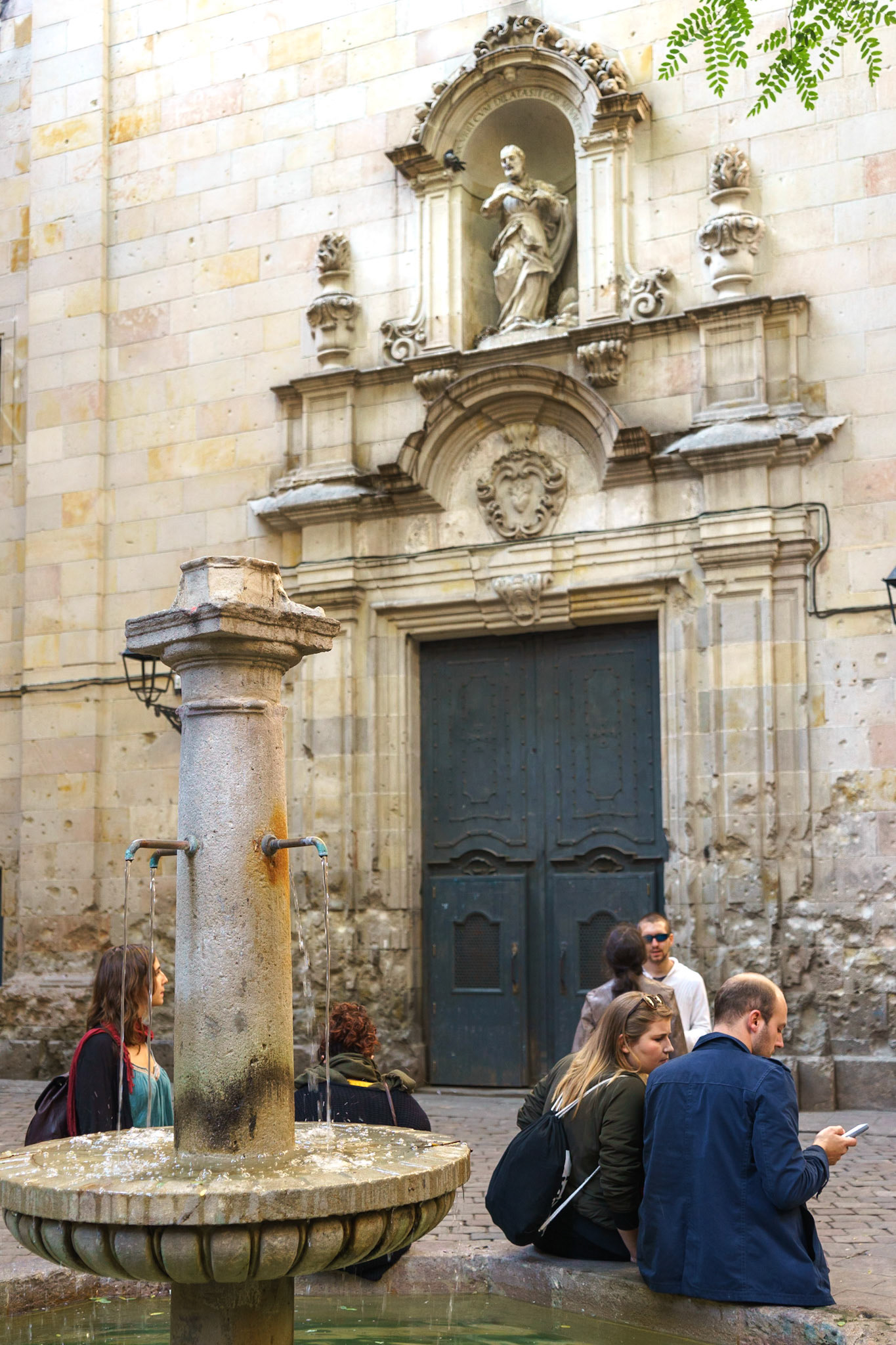 Vicky Christina Barcelona filminde bir sahnenin geçtiği, ekibin oturduğu masadan görünen kilise ve çeşmenin manzarası. Kilise duvarlarında görülen harabiyet, 2. Dünya Savaşı sırasında bu küçük meydanın bombalanmasıyla meydana gelmiştir.