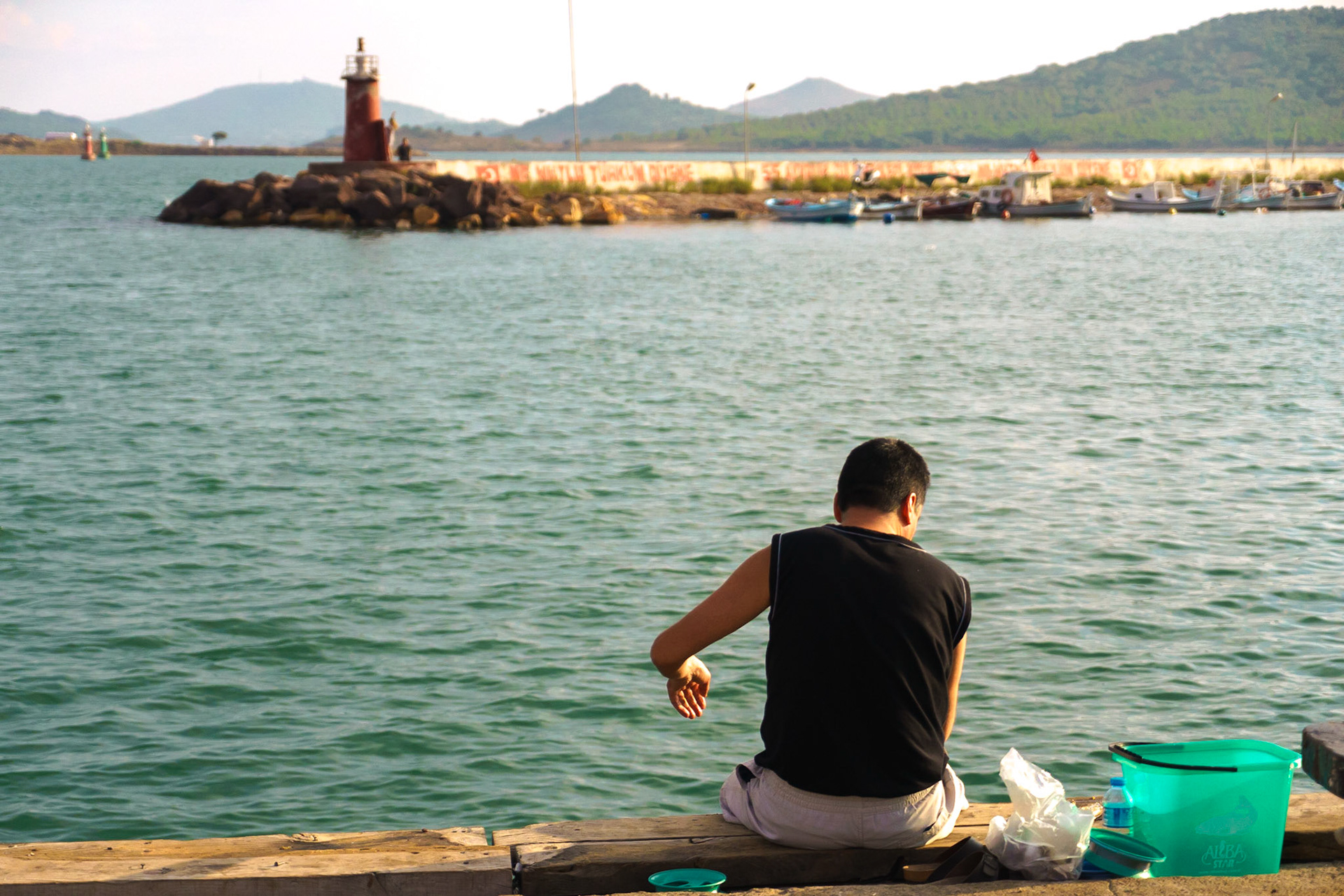 Günbatımında yüzünü Ayvalık tarafına dönerek balık tutan bir Cunda sakini.