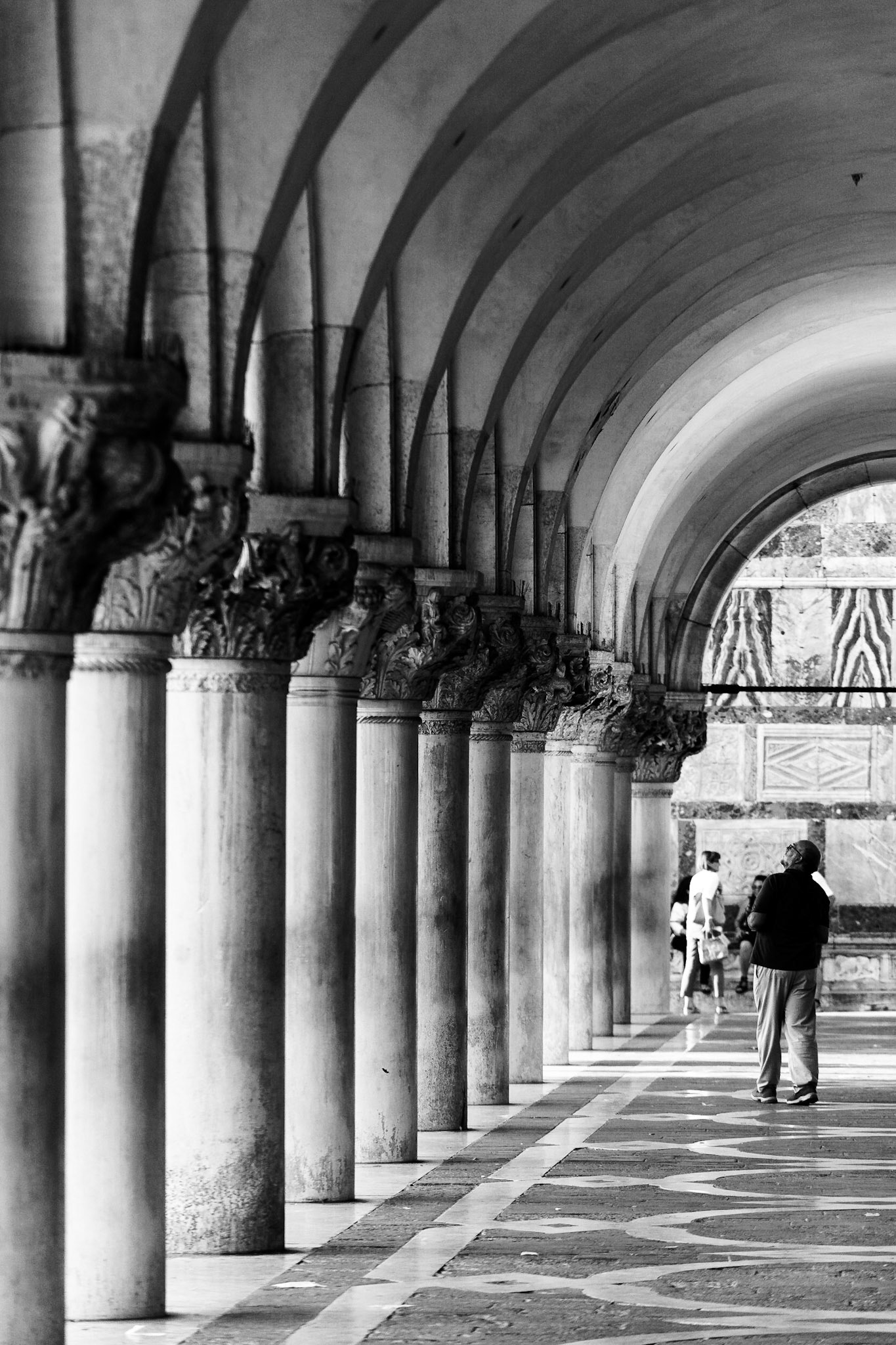 Dükler Sarayı'nın dış cephesinde yer alan sütun ve kemerlerin tekrarlayan düzeni büyüleyici bir görüntü oluşturuyor.