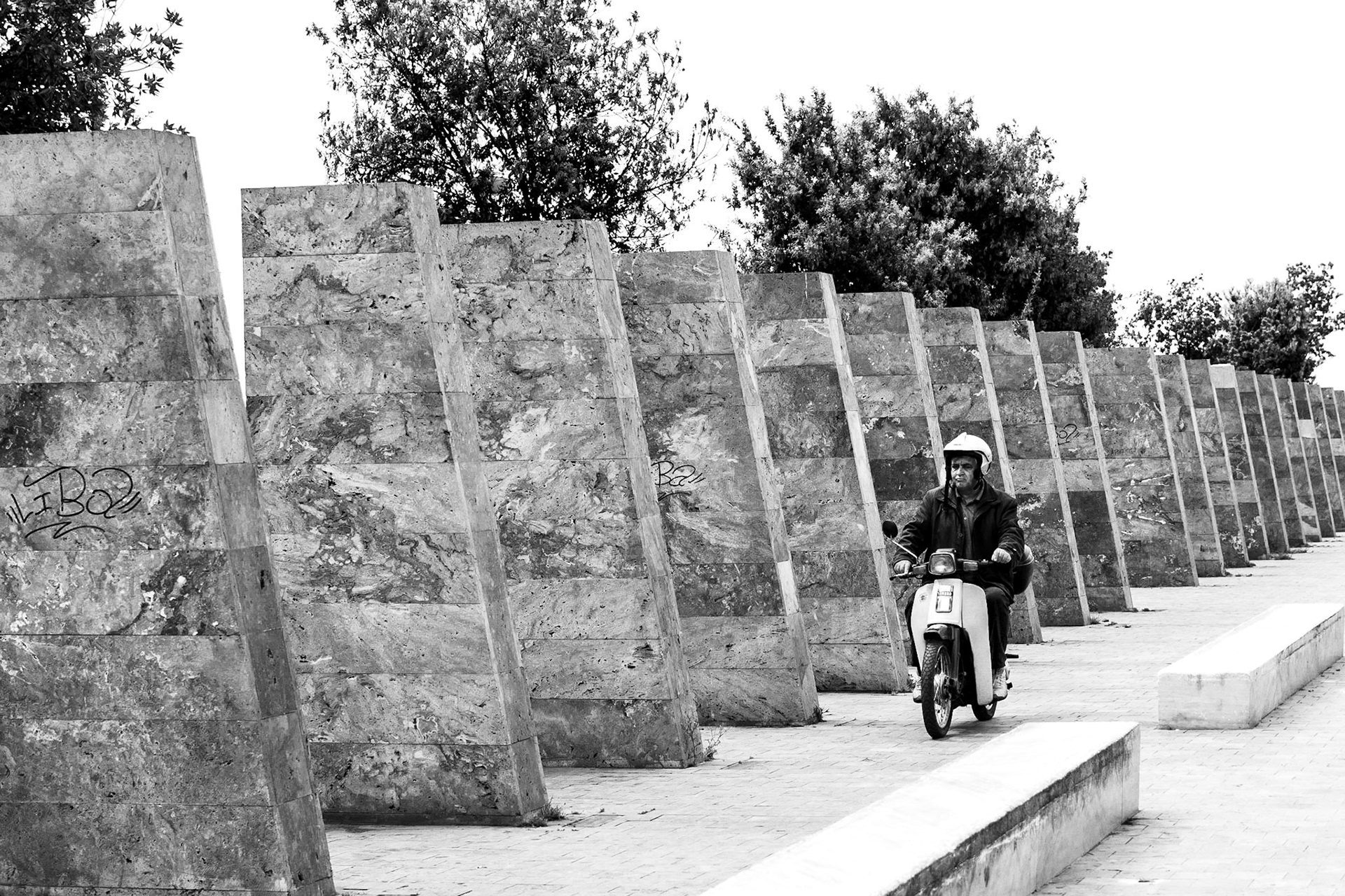 Selanik'te bir yaya bölgesinde bulunan sıralı anıtların önünden motorsikletiyle geçen bir kişinin oluşturduğu görüntü, aslında Yunanların bizden çok farklı olmadığını düşündürüyor.