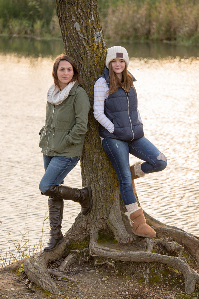 Mom and teen daughter leaning against a tree in front of the pond at Burke Park