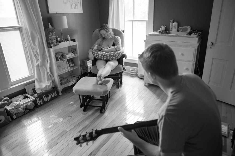 Father playing guitar for mom and child while breastfeeding