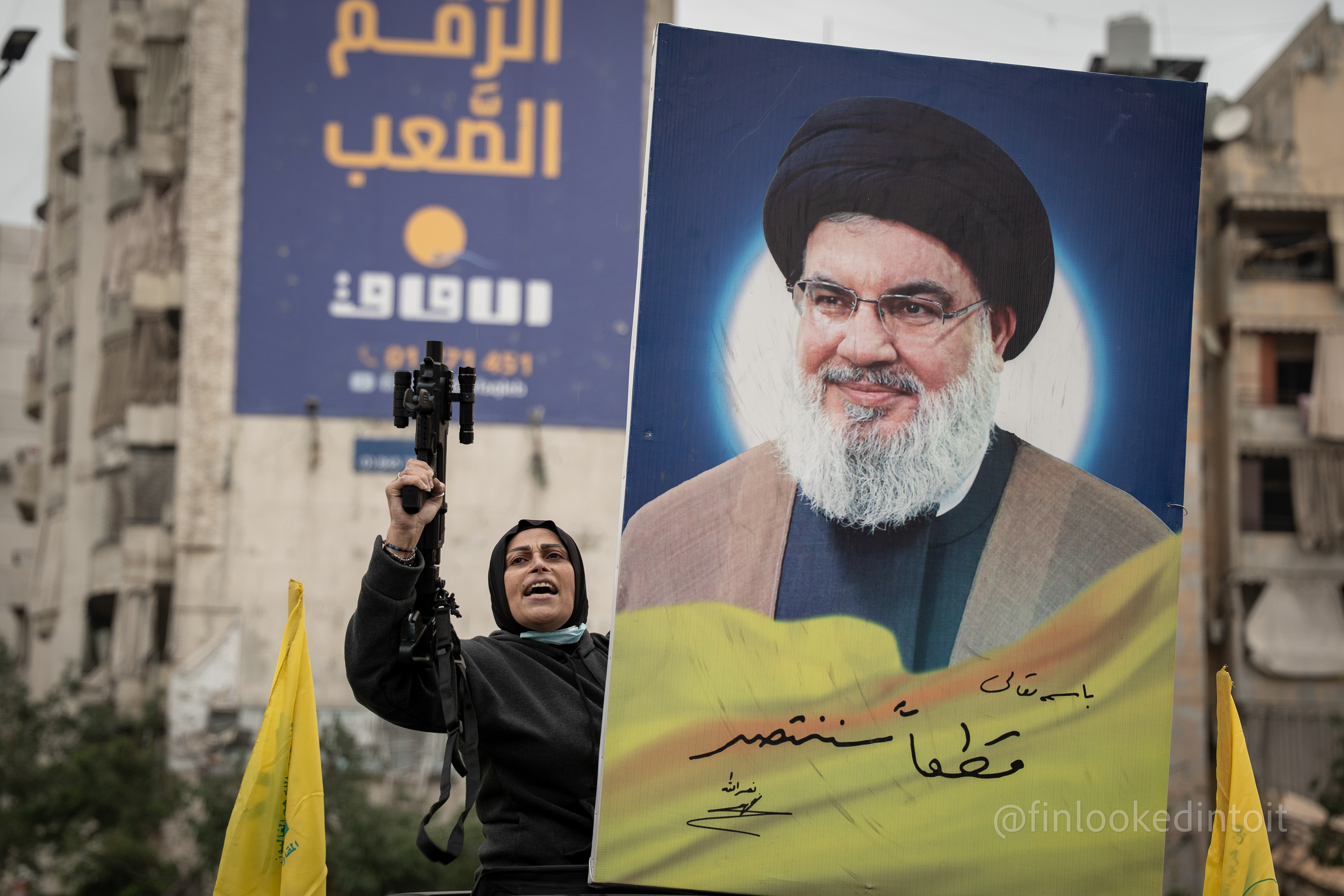 A Lebanese women brandishes a modified pistol next to a portrait of the late Hassan Nasrallah, Dahieh, Lebanon, 11/27/2024
