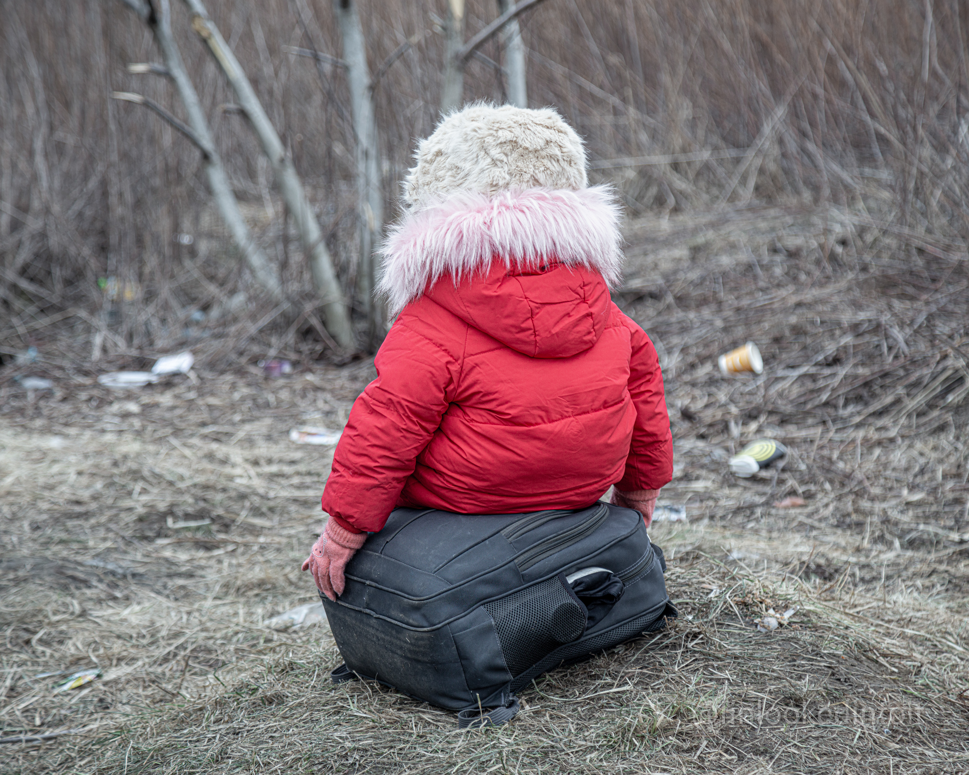 A Ukrainian child rests on her suitcase before crossing the Polish border, 03/01/2022