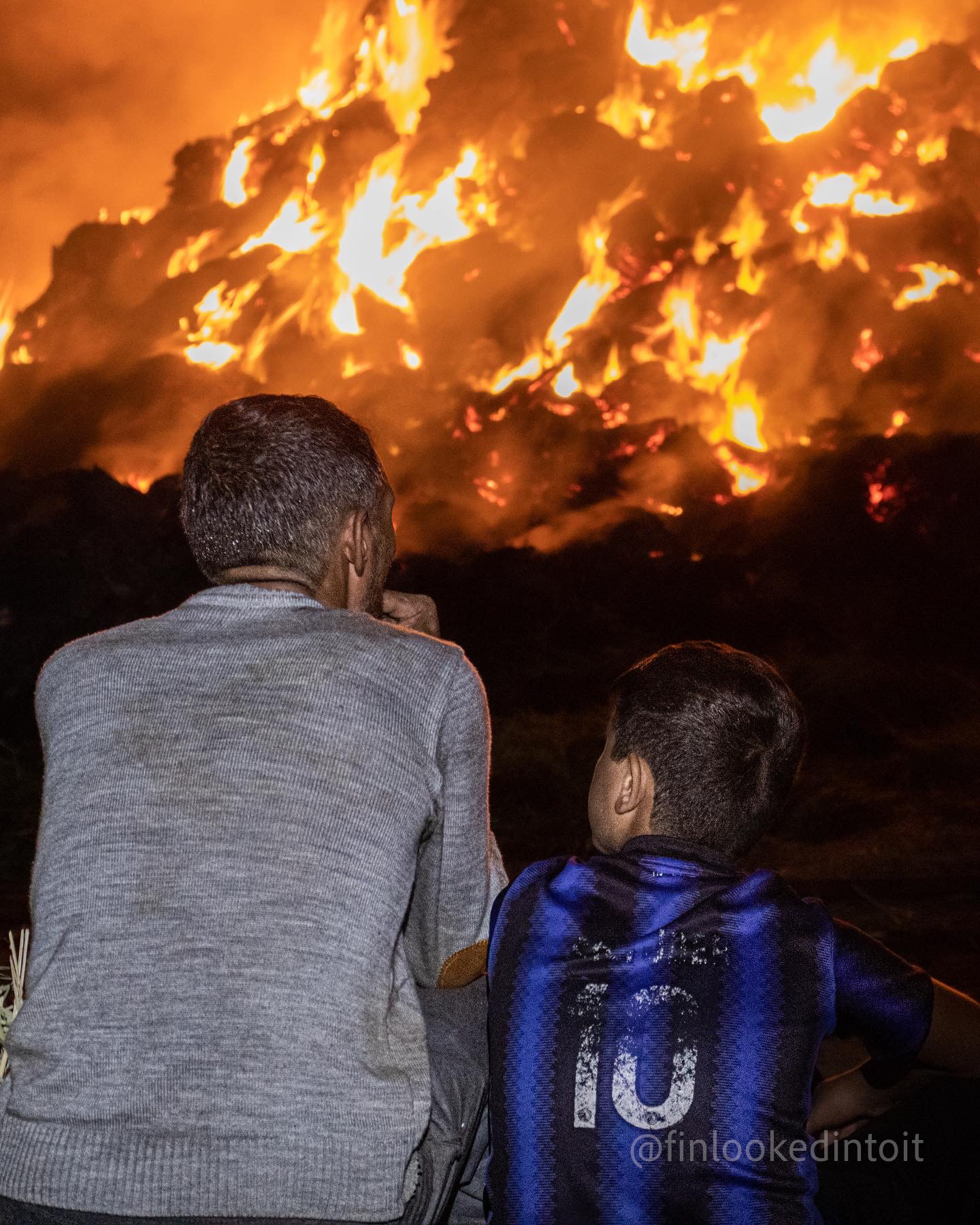 An Armenian father and son watch their harvest burning in the village of Yeraskh after it was lit ablaze by Azerbaijani gunfire, 10/24/2021