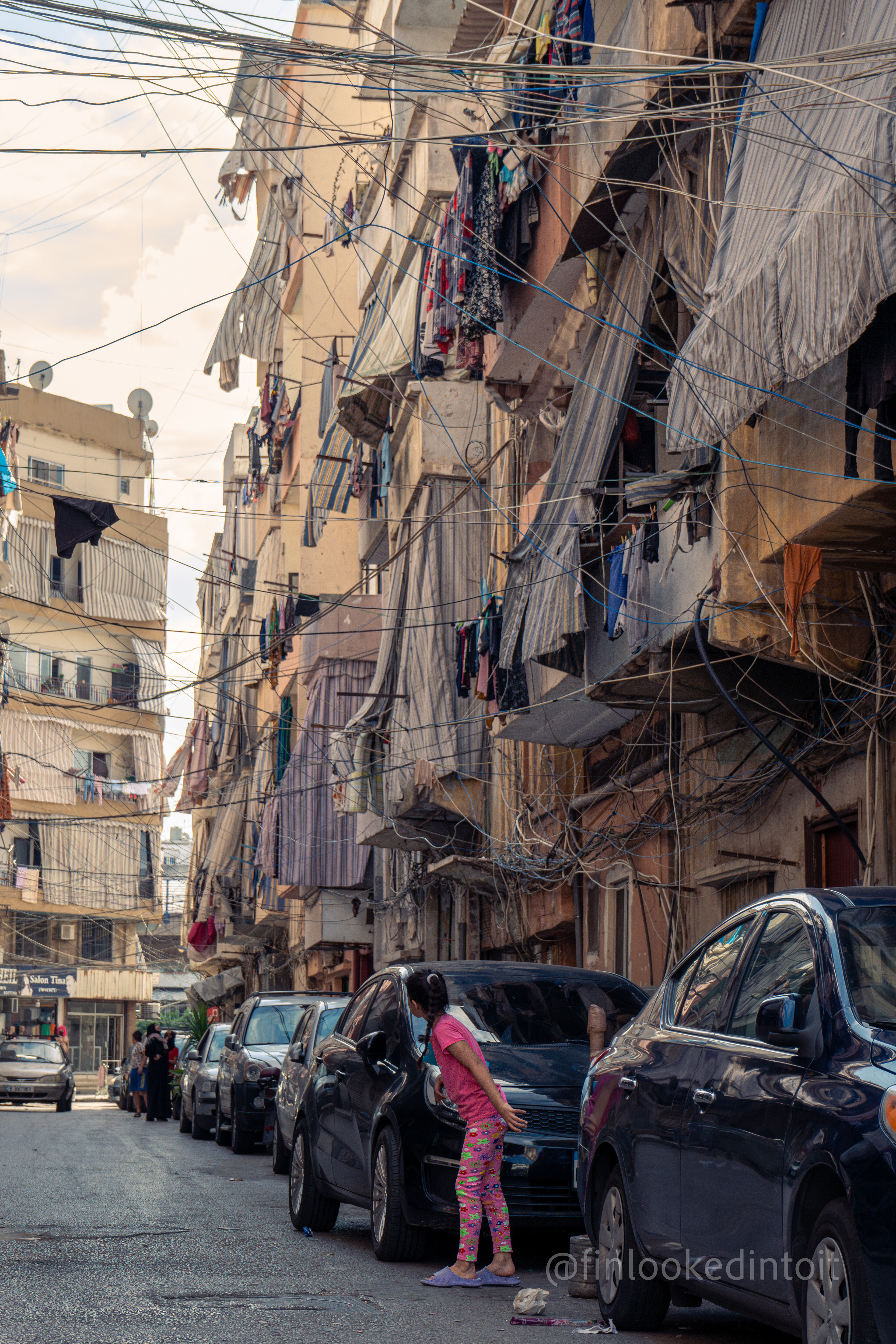 A Lebanese girl beneath the rats nest of electrical wiring so typically seen across the Middle East,  10/17/2023