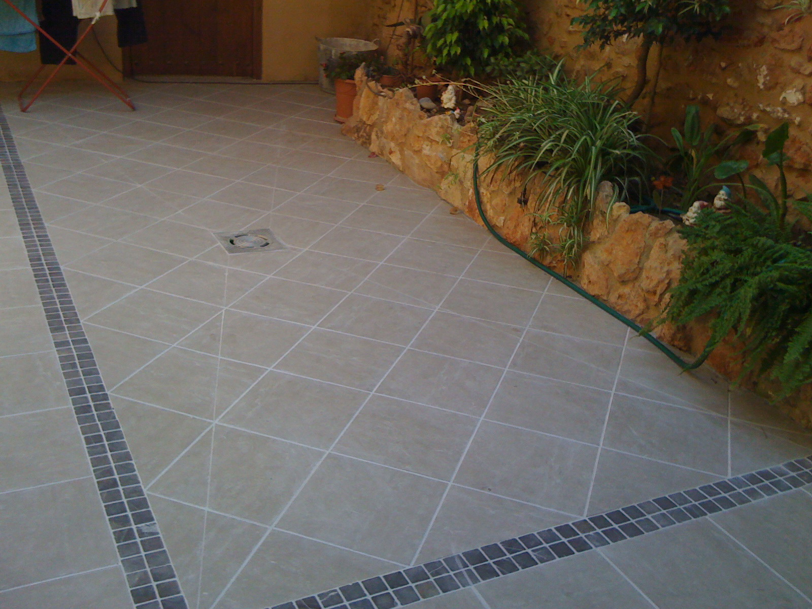 Suelo finalizado sacando planos inclinados al desagüe en la zona central y enmarcado con mosacio de piedra