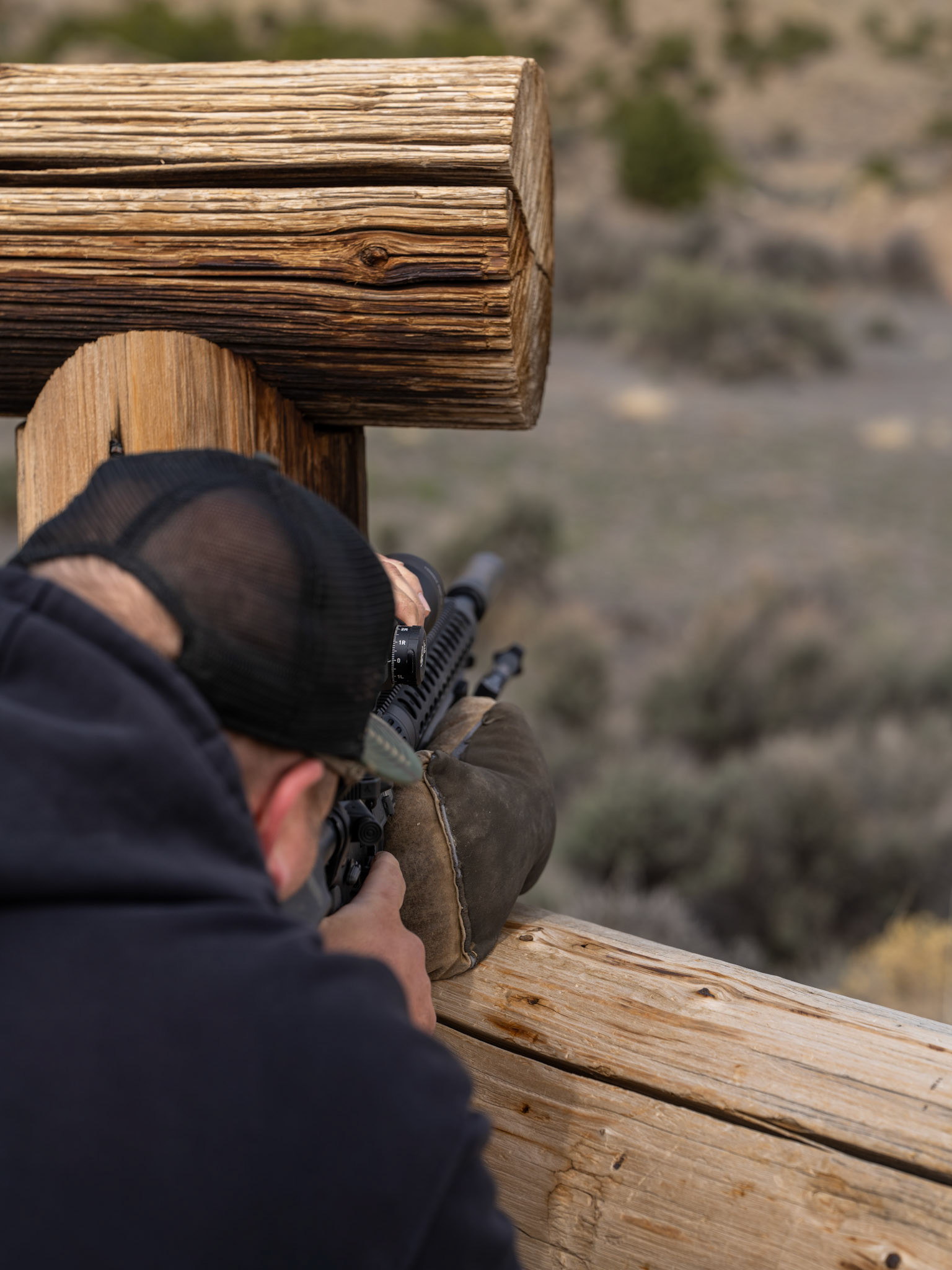 Close-up over the shoulder of Precision Rifle Shooter on Hitching Post Barricade