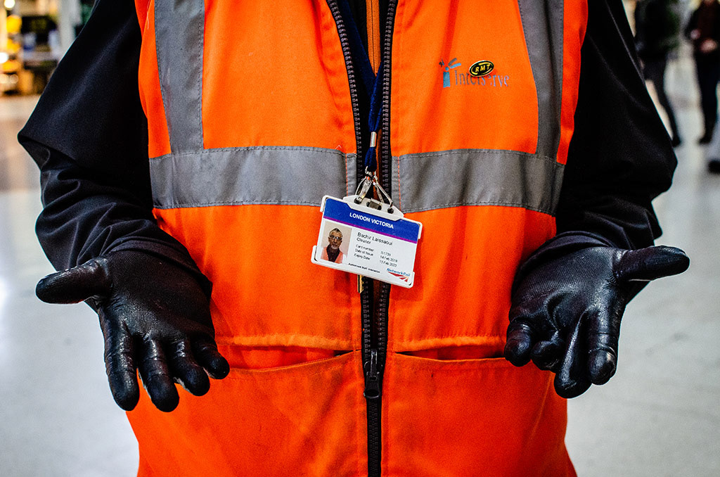 Bachir, a cleaner working for Network Rail in Victoria Station, presents his gloved hands and displays his work ID in London, England, November 24, 2018. 
