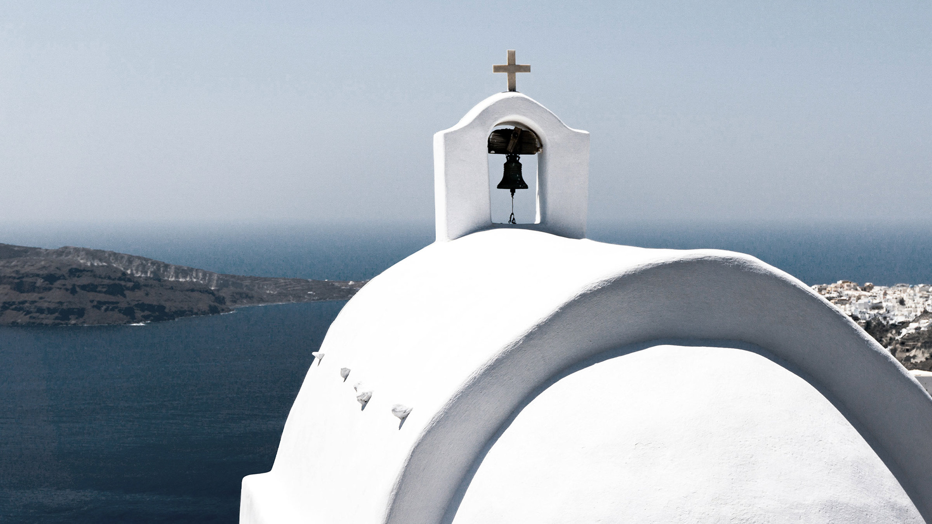 A white church in Santorini, with characteristic cycladic architecture, overlooking the sea.