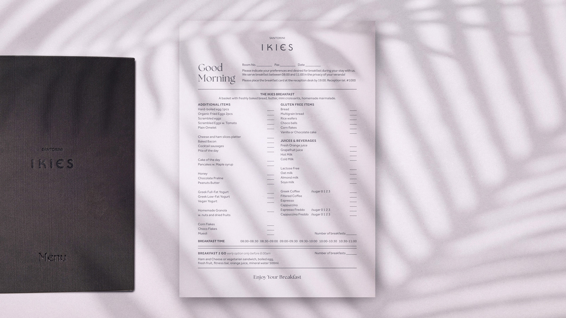 IKIES Santorini boutique hotel menu design, closed, showcasing the PU leather cover with embossed logo and title. At the center of the image lies an A4 breakfast form, meant to be filled out by guests.