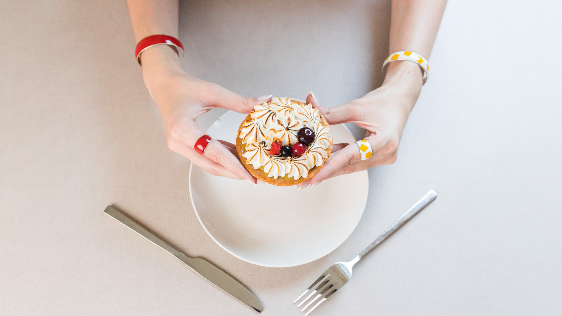 Woman's hands holding a cupcake, wearing AleGio silver rings and bracelets.