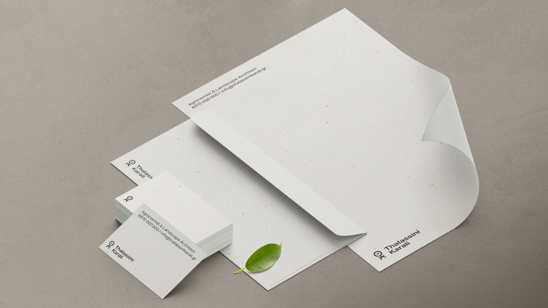 Thalassini Karali agronomist and landscape architect custom designed stationery system. The system includes a stack of professional business cards, envelope and letterhead that feature the initials logotype and are all made from recycled paper. These are all placed next to each other and with a small leaf on top of the envelope.
