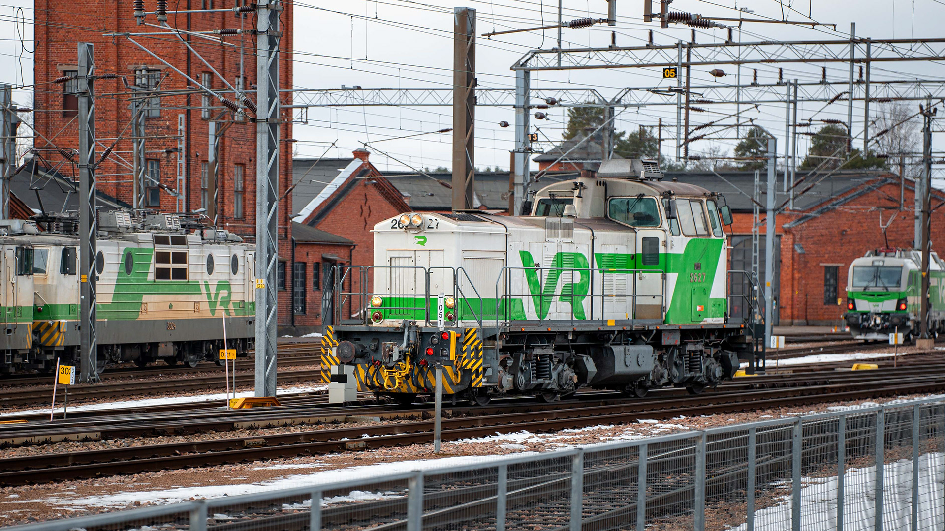 Dv12-dieselveturi palaamassa Kuusankosken tehdasratapihalta Kouvolan varikolle. Taustalla Sr1- ja Sr3 sähköveturit. (1.2.2025)§