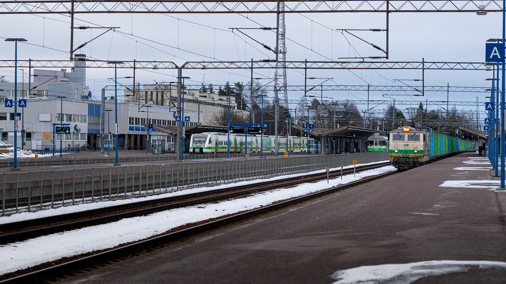 Kouvolan rautatieasema, jossa Sr1-veturi kuljettaa puutavaravaunuja Kouvolan lajittelusta Pieksämäelle. Asemalla myös lähtöä odottavat Sm2-lähijuna sekä Sm3-pendolinojuna. (1.2.2025)