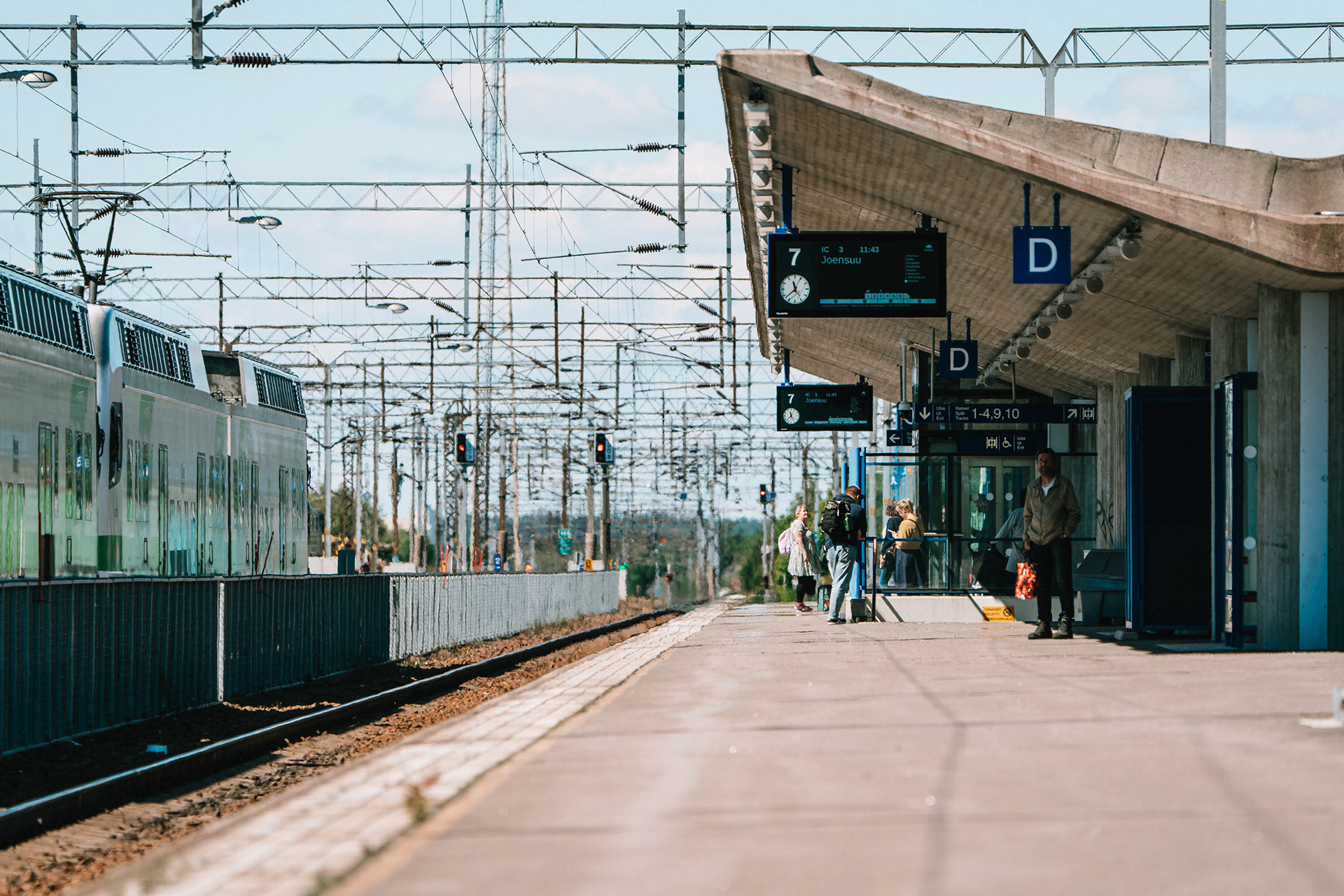 Rautatieasema, jossa ihmiset odottavat Joensuuhun menevän junan saapumista.