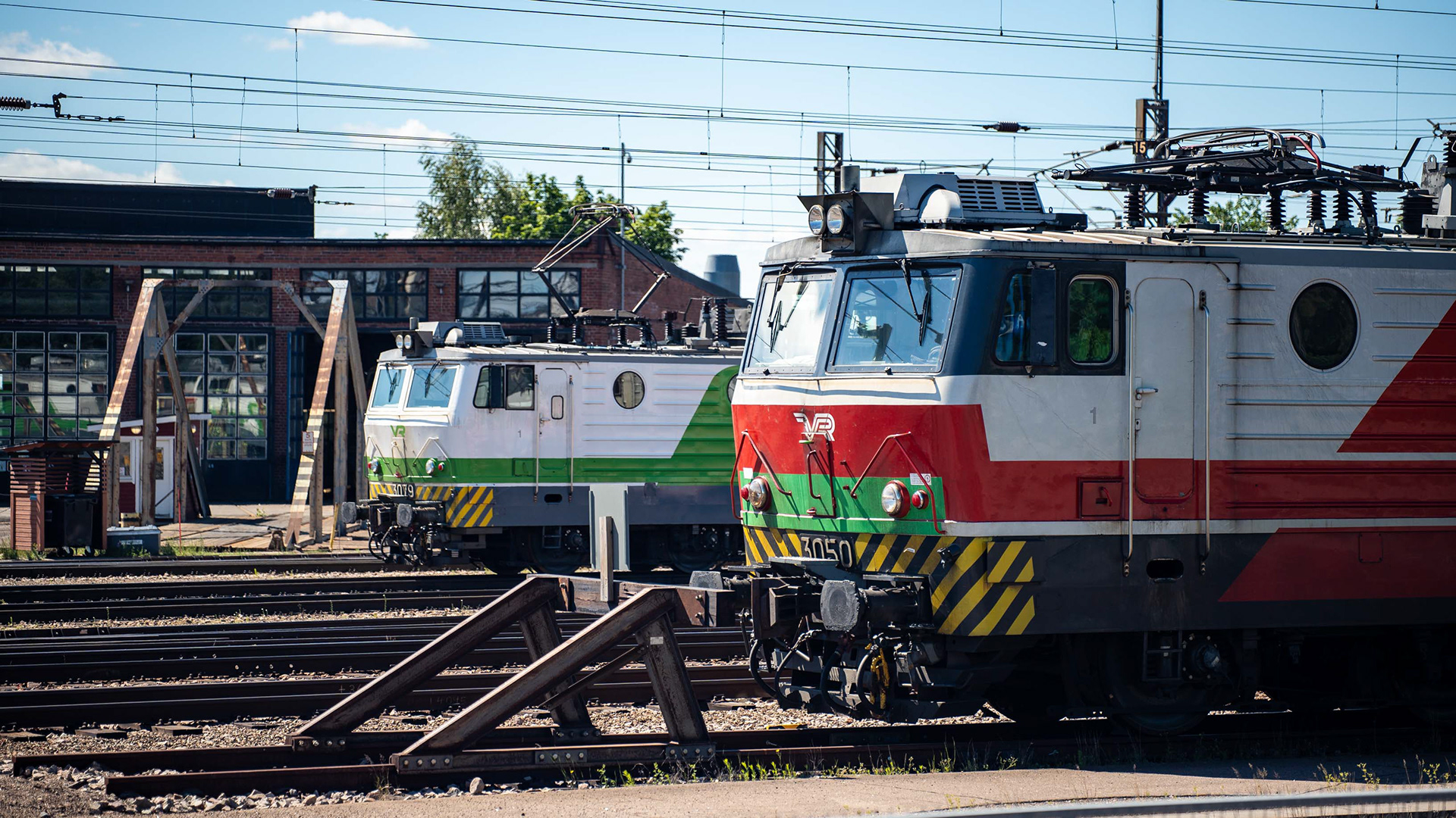 Vanhemmalla punaisella värityksellä oleva Sr1 3050 ja uudemmalla vihreällä värityksellä oleva Sr1 3079 Kouvolan veturitallien edustalla. (15.6.2024)