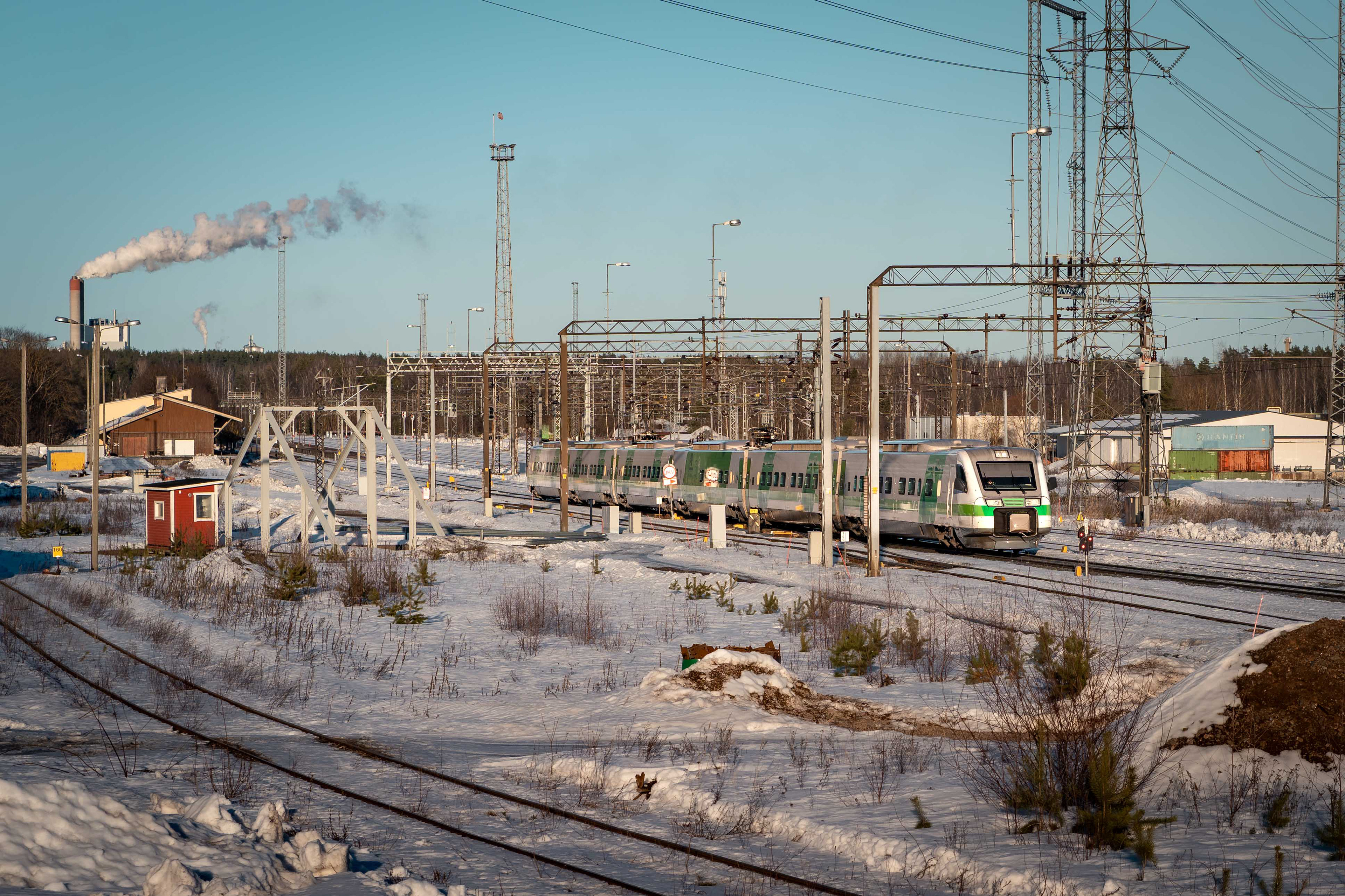 Lappeenrannan rautatieaseman länislaitaa. Kuvassa Sm3-pendolinojuna lähdössä Lappeenrannasta kohti Helsinkiä. Taka-alalla vasemmalle UPM Kaukaan tehtaan piippu. (7.3.2026)