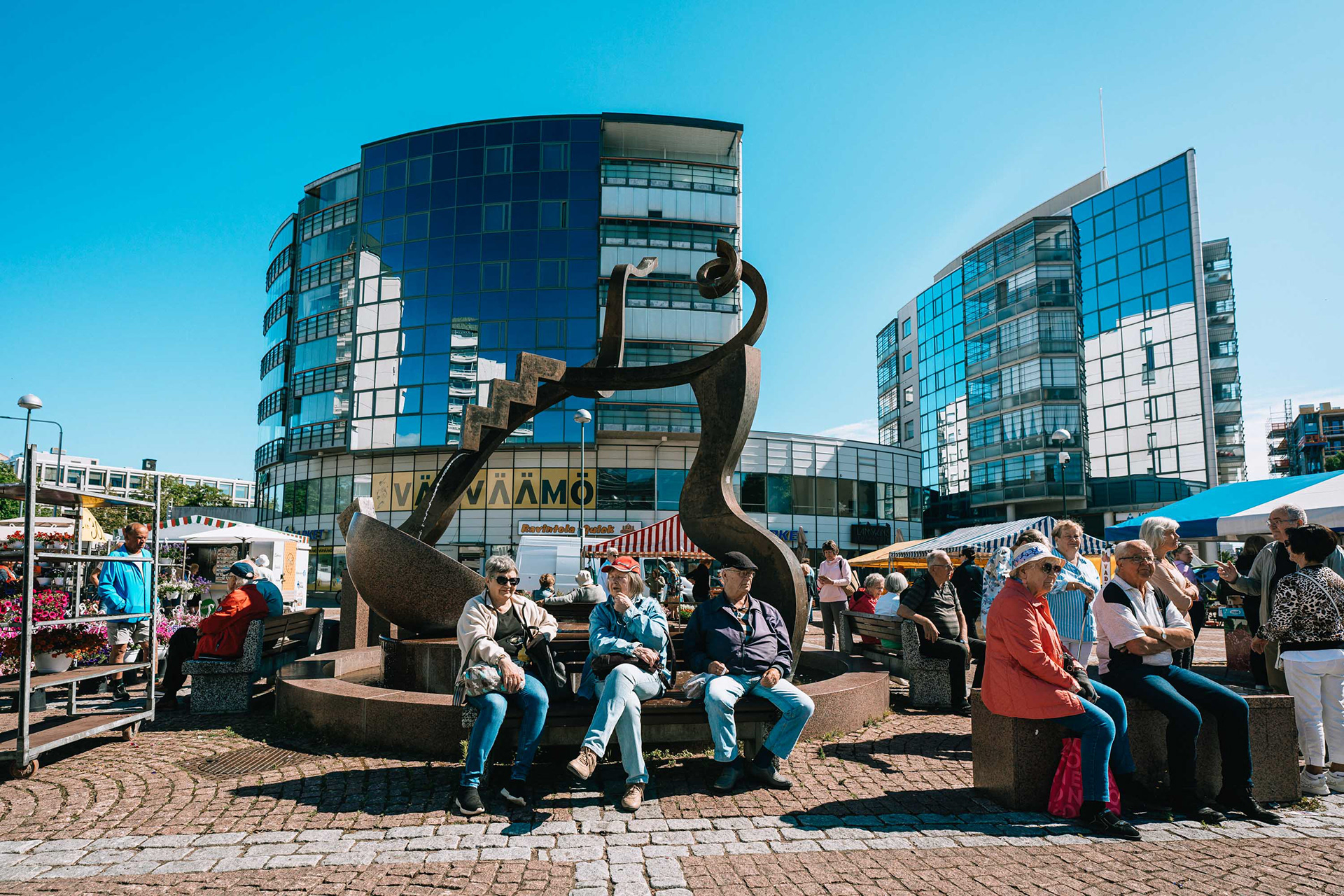 Kaupunkilaisia kauppatorilla. Keskellä torin suihkulähde.