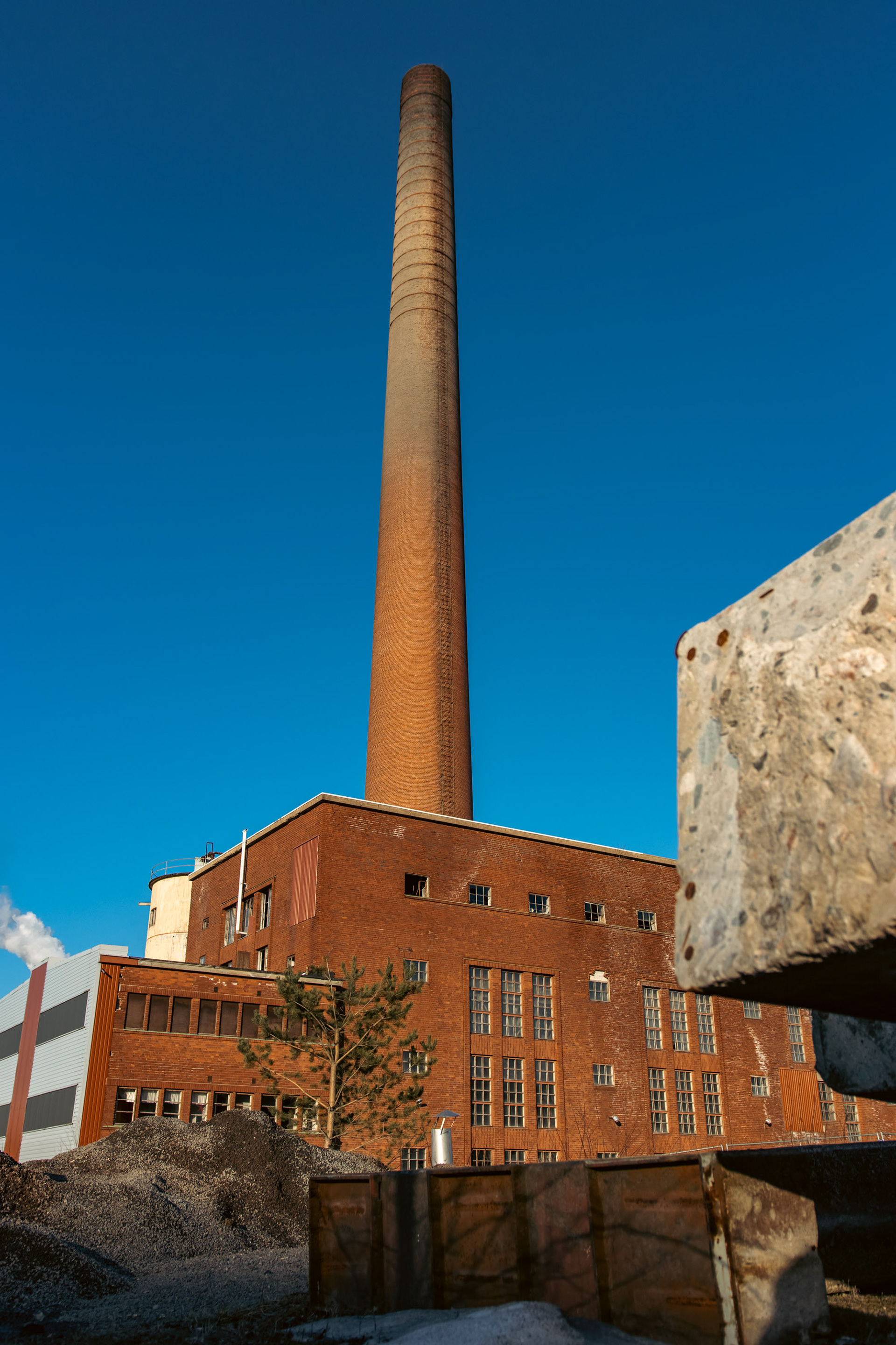 Vuonna 1936 valmistunut Kymintehtaan vanha höyryvoimalaitos. Laitoksen tiilinen piippu on 121 metriä korkea. (4.2023)